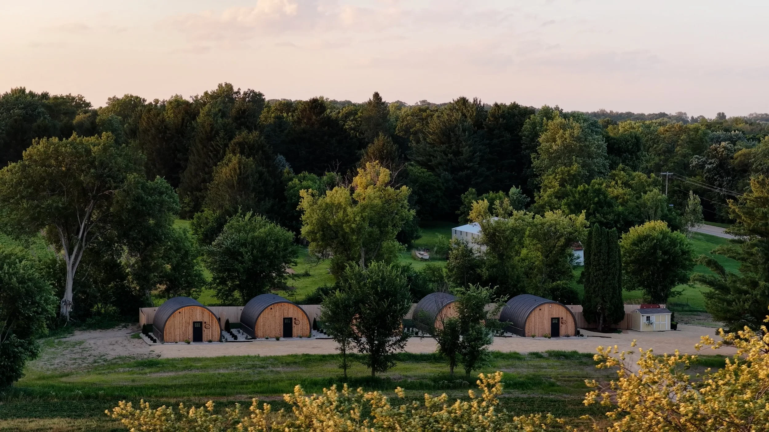 An elderly woman and a man at a bakery stand, with packaged baked goods on the counter, in a wooden interior setting.