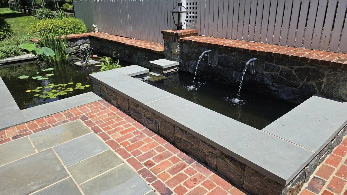 Raised pond with twin fountains, bluestone coping and a brick patio — Brandywine Designs