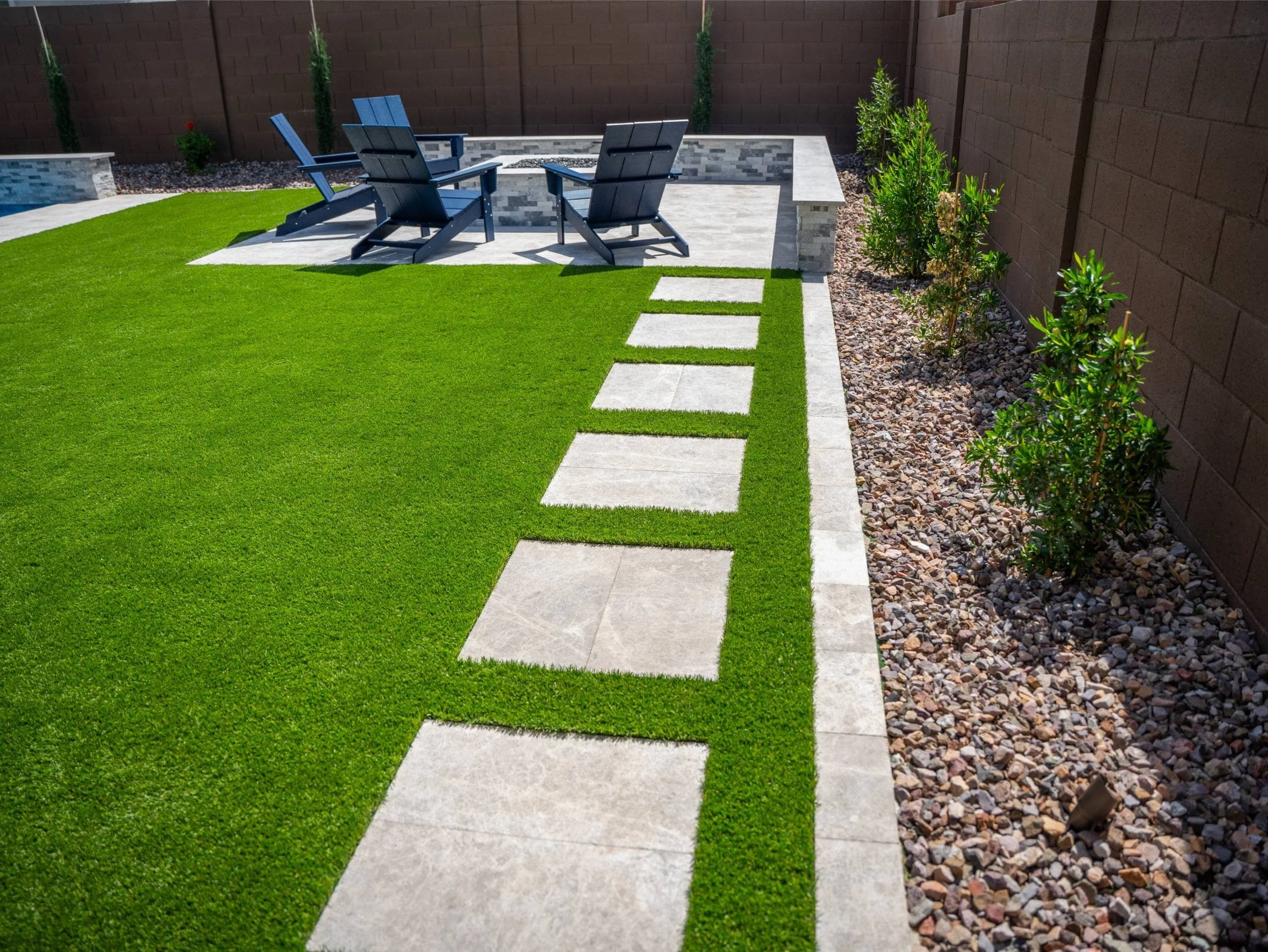 A walkway in Arcadia, AZ with straight pavers set in artificial turf as part of landscape design.