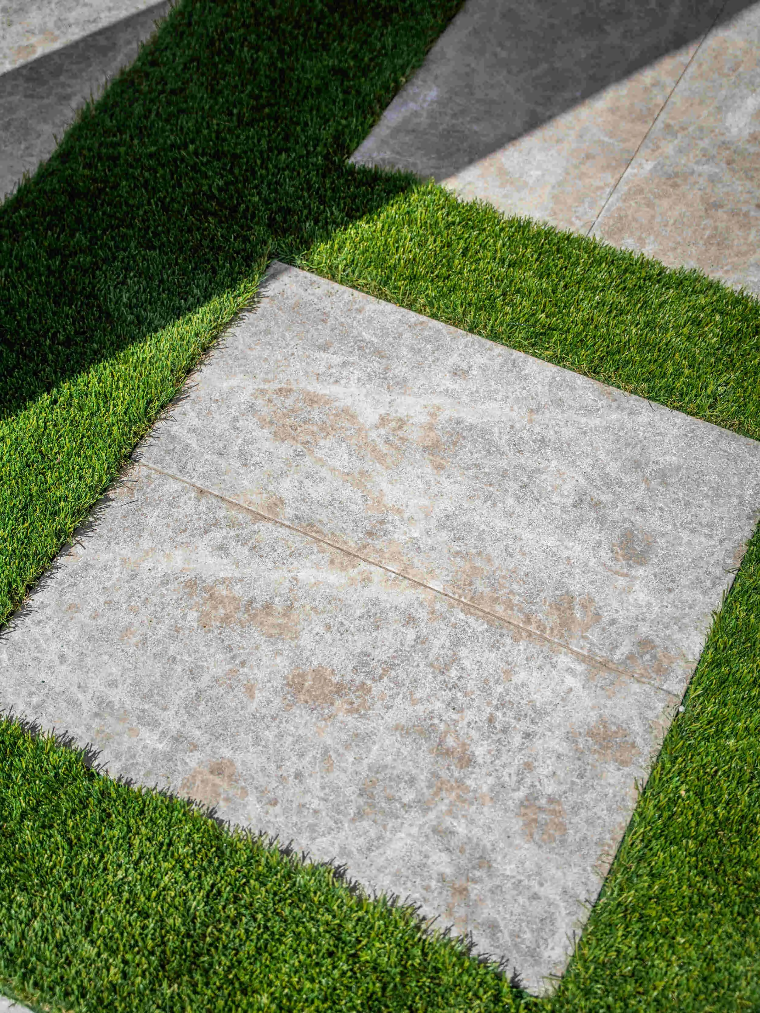 Close-up of paver walkway set in artificial turf in Gilbert, AZ showing clean landscape design lines