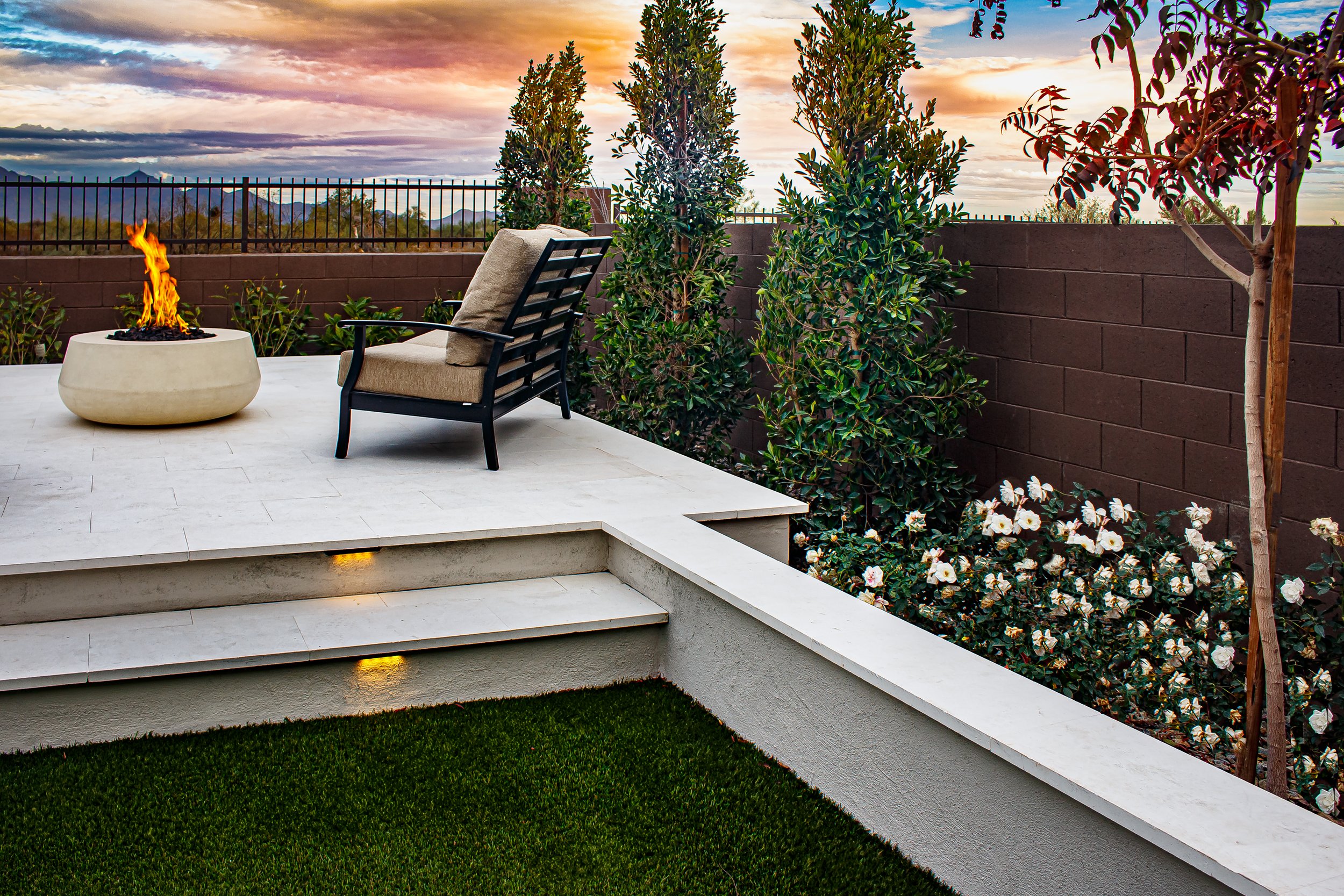 A raised planter box with layered plantings and young trees in Chandler, AZ for a structured landscape design