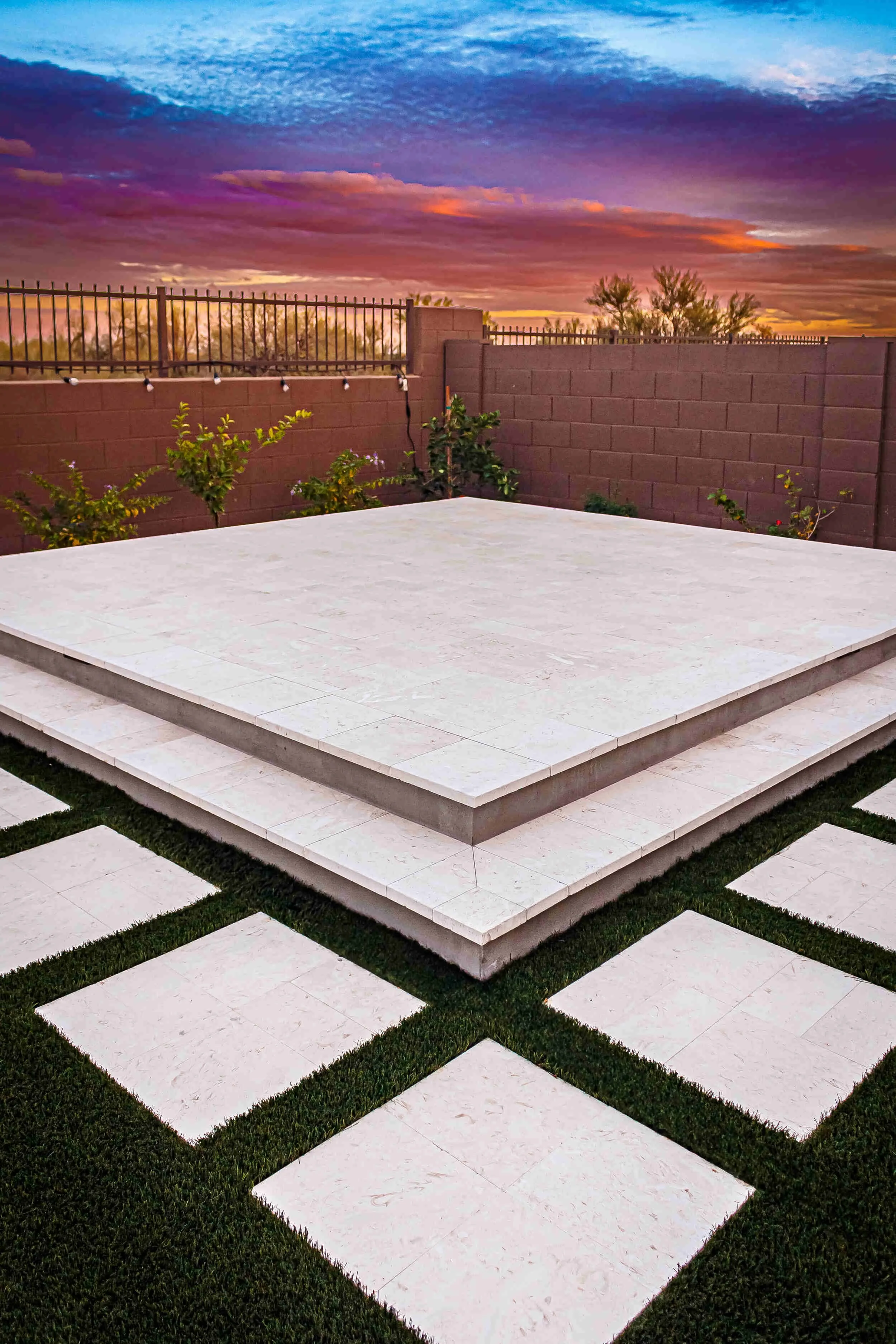 Raised patio platform in Surprise, AZ with step pads in artificial turf as part of custom landscape design