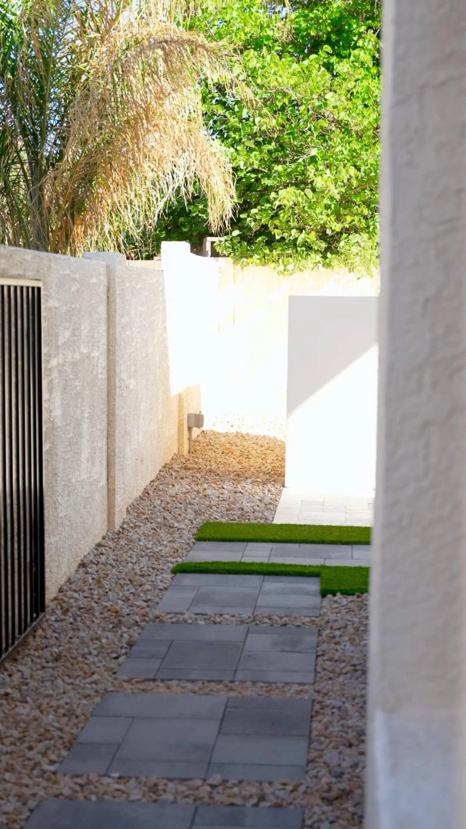Narrow side-yard walkway in Gilbert, AZ with pavers, gravel and artificial turf integrated into landscape design