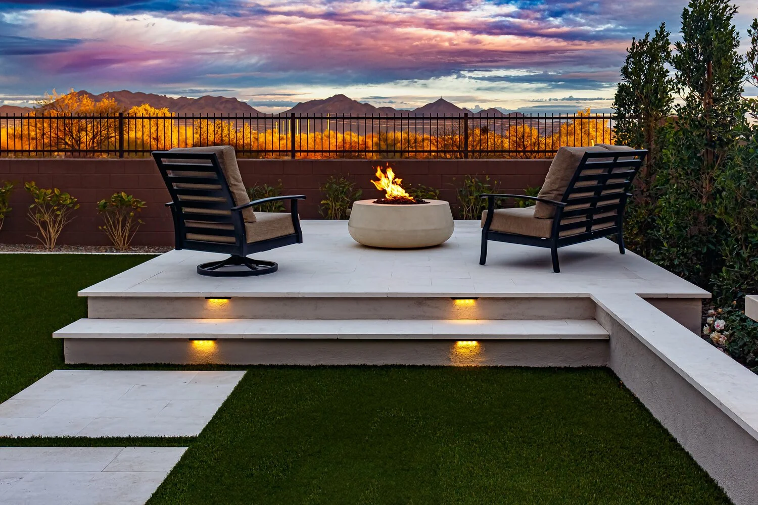 Fire features with lava rock creating warm ambiance near turf and concrete steps in Arcadia, AZ