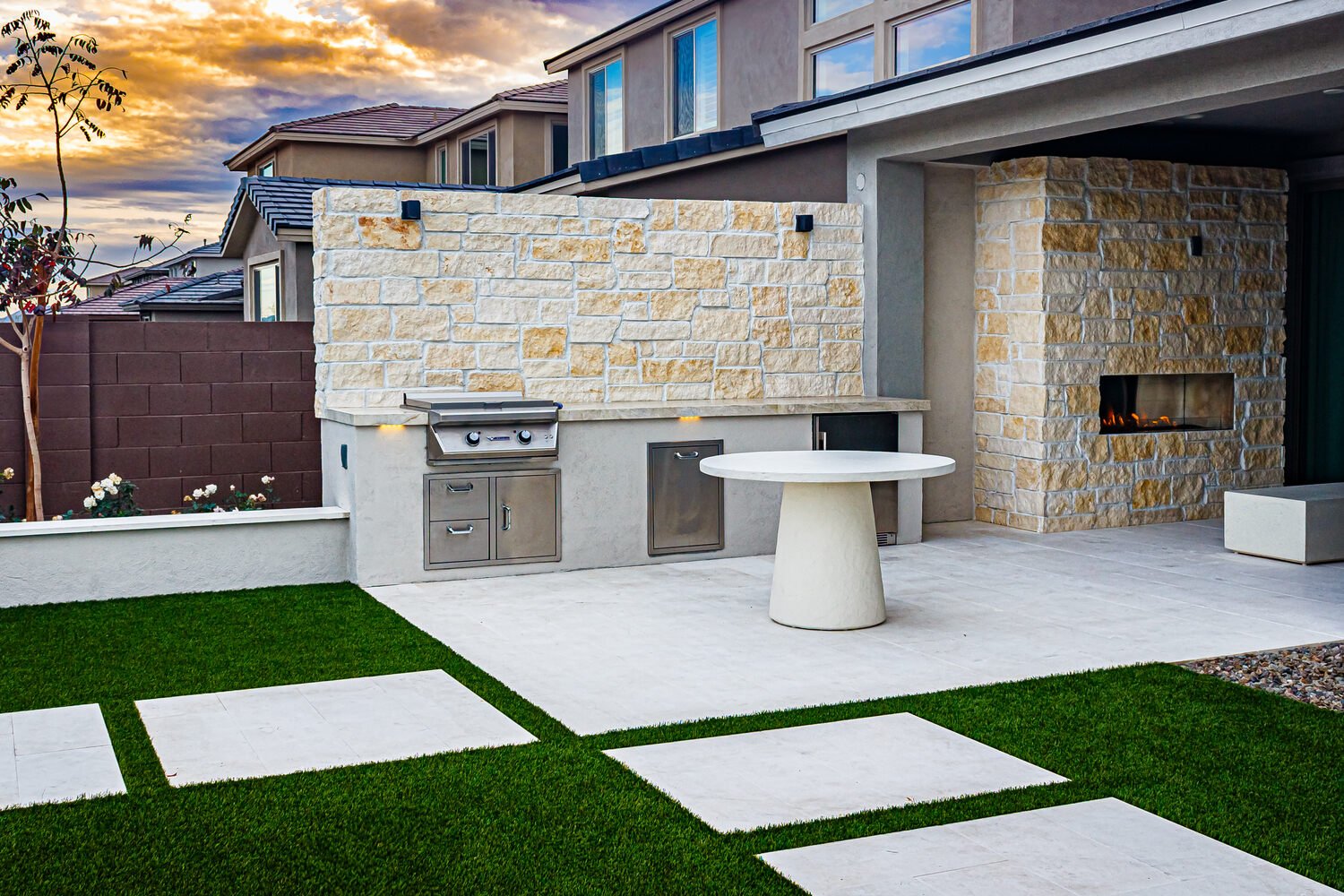 Outdoor kitchen and dining space in Surprise, AZ with artificial turf and clean landscape design