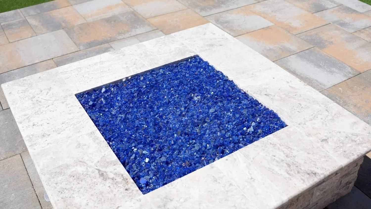 A contemporary fire feature with vibrant blue fire glass designed for patios and walkways in Chandler, AZ