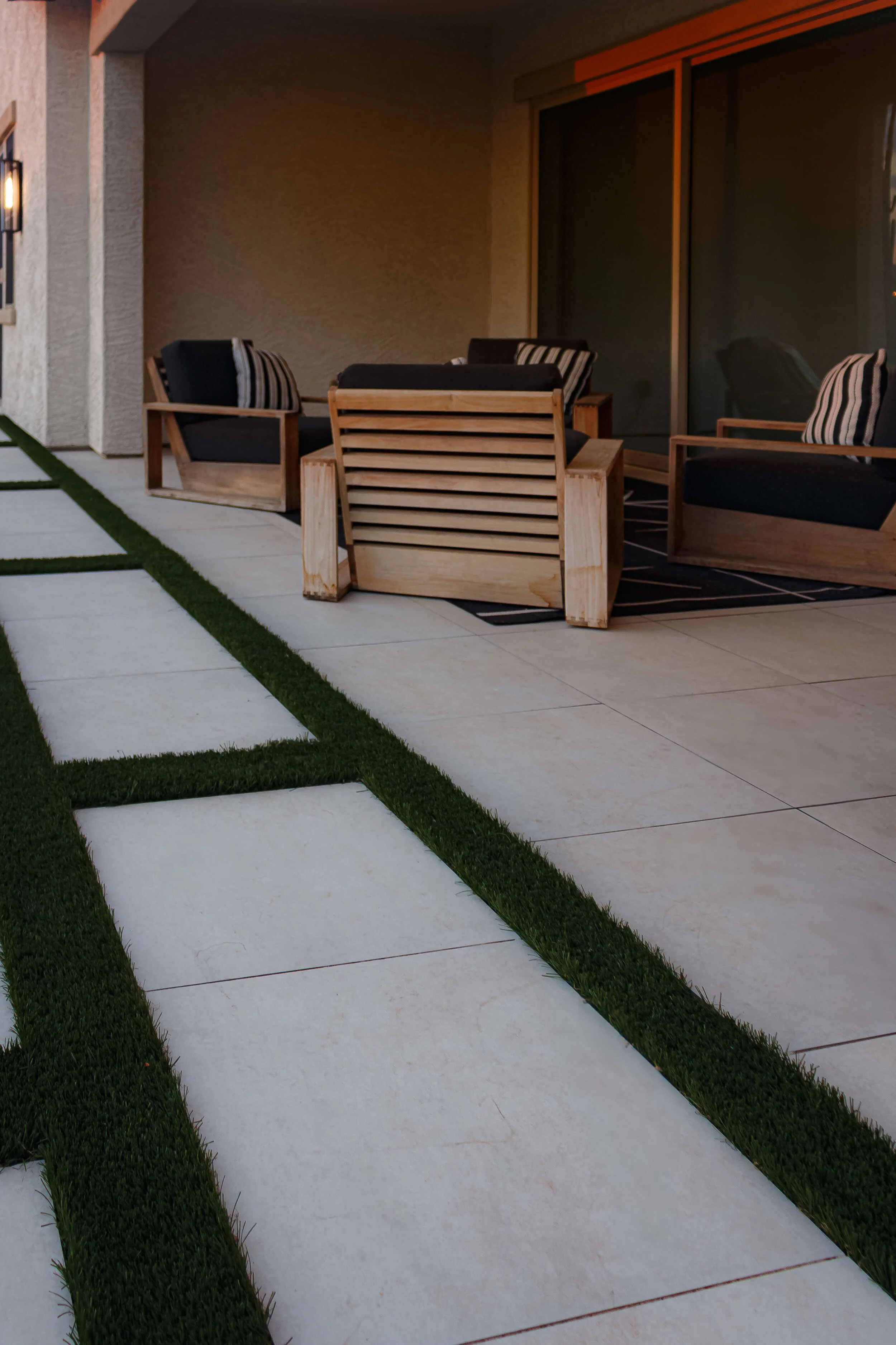 Modern patio seating area in Arcadia, AZ with large pavers and artificial turf used in landscape design