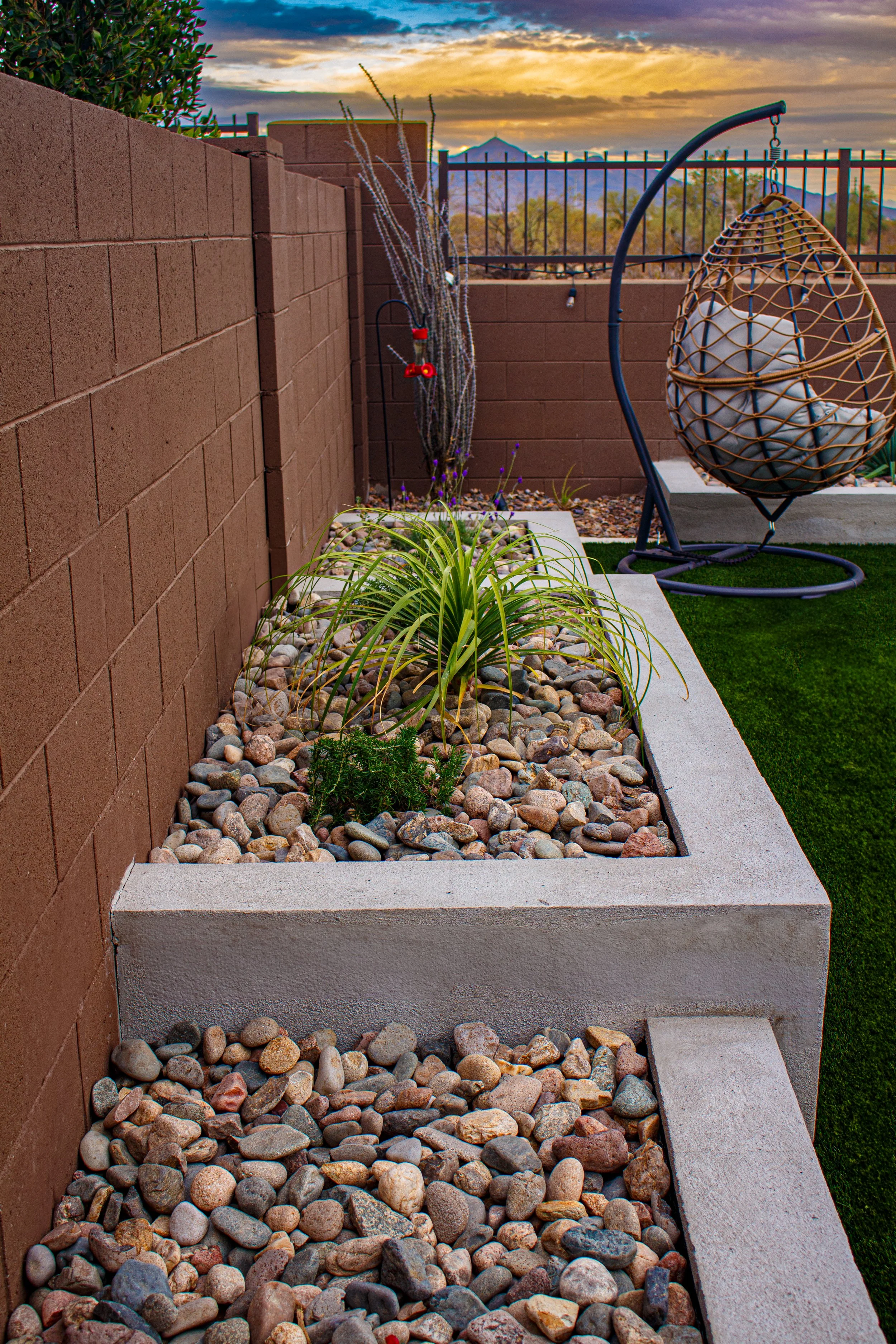 A raised planter box with desert plantings and decorative rock in Paradise Valley, AZ beside a modern outdoor seating area