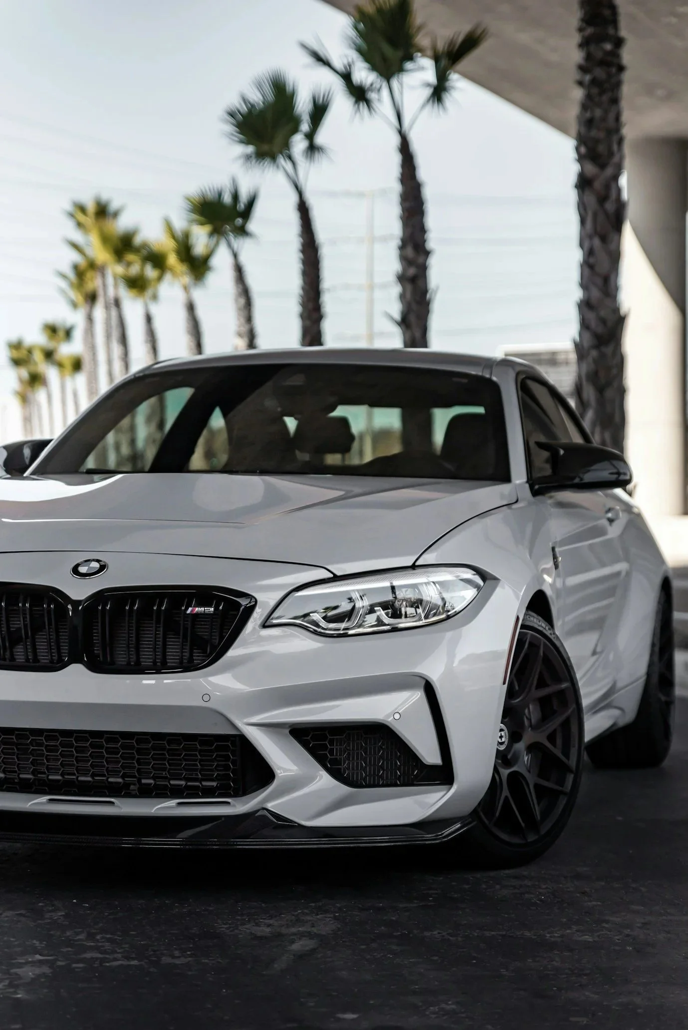 Close-up of processed white car being washed, with soap foam covering the surface and a blurred background of car doors.
