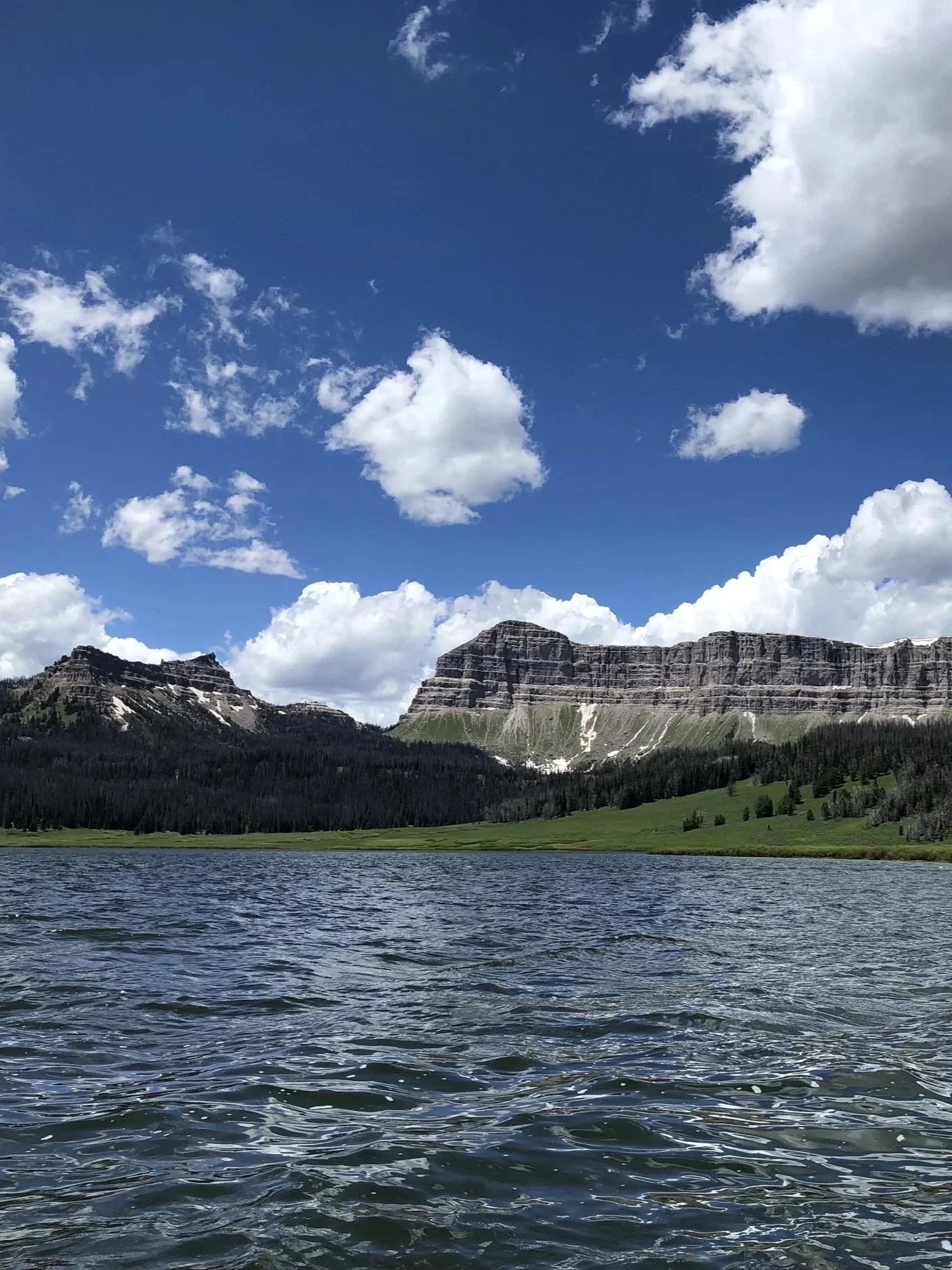 Photo of lake taken in July 2022 in Wyoming. The sky is a deep blue and cloudy.