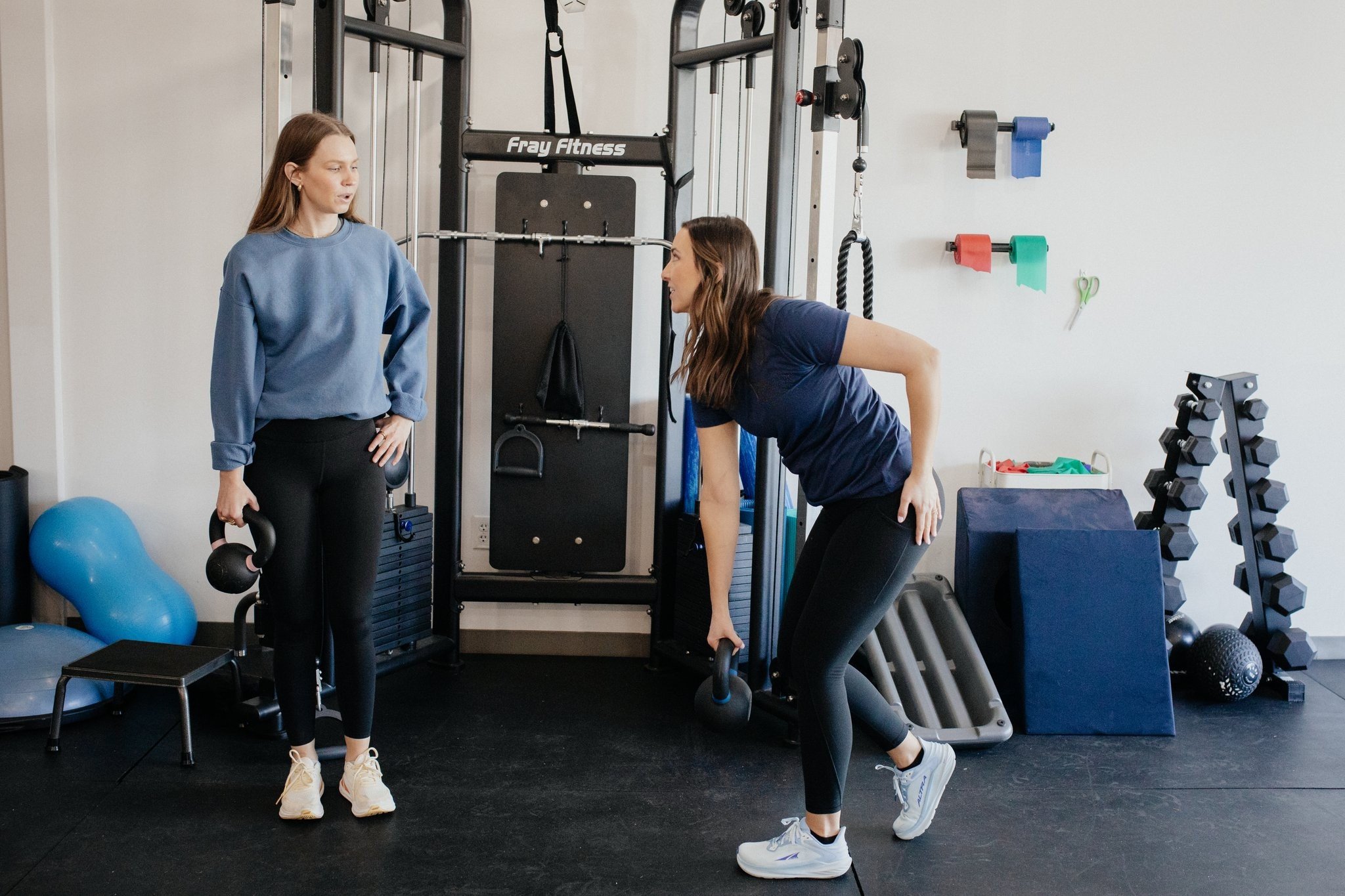Pelvic floor physical therapist helping patient lift weights without pain.