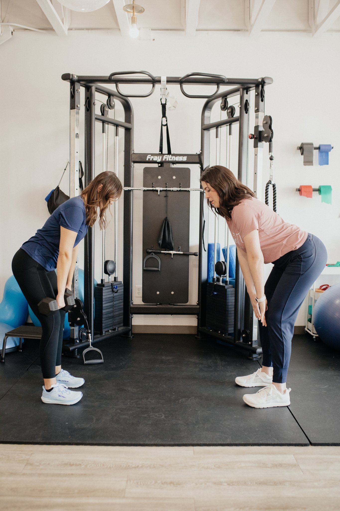 Physical therapist training a patient on deadlifts in a gym.