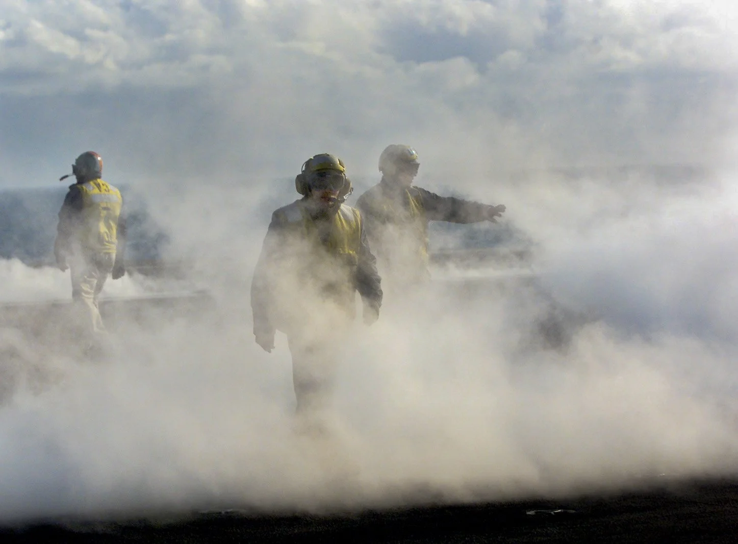 Sailors walk through the steam generated by the catapult after the launch of fighter jet on the flight deck of the USS Abraham Lincoln before sailing to Iraq in 2002.