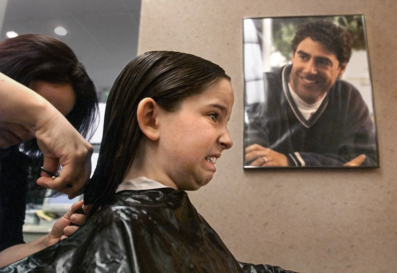 A nervous Tricia Carson, 9, winces as hairstylist Marsci Beach cuts almost a foot of her hair, which will be donated to Locks of Love.