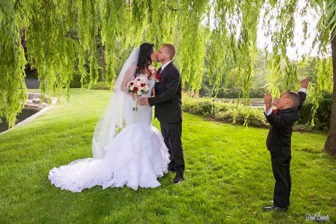 Wedding photo taken at Glen Oaks woth a son watching mom and dad kissing.jpg
