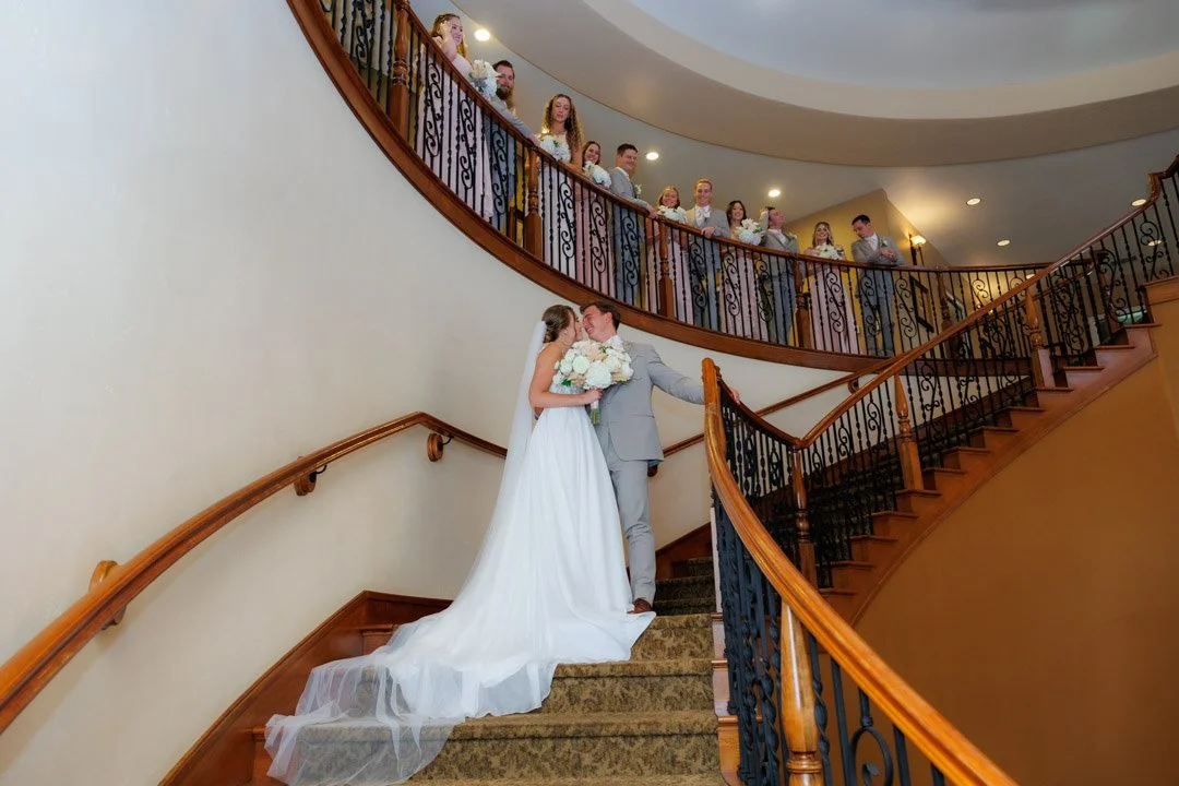 A couple enjoying a moment on the stairs at Wilson Creek winery in Temecula, California with the wedding party the watching