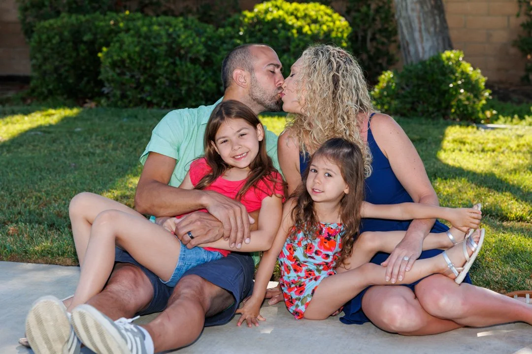 Mom and dad kissing in the background of a family portrait