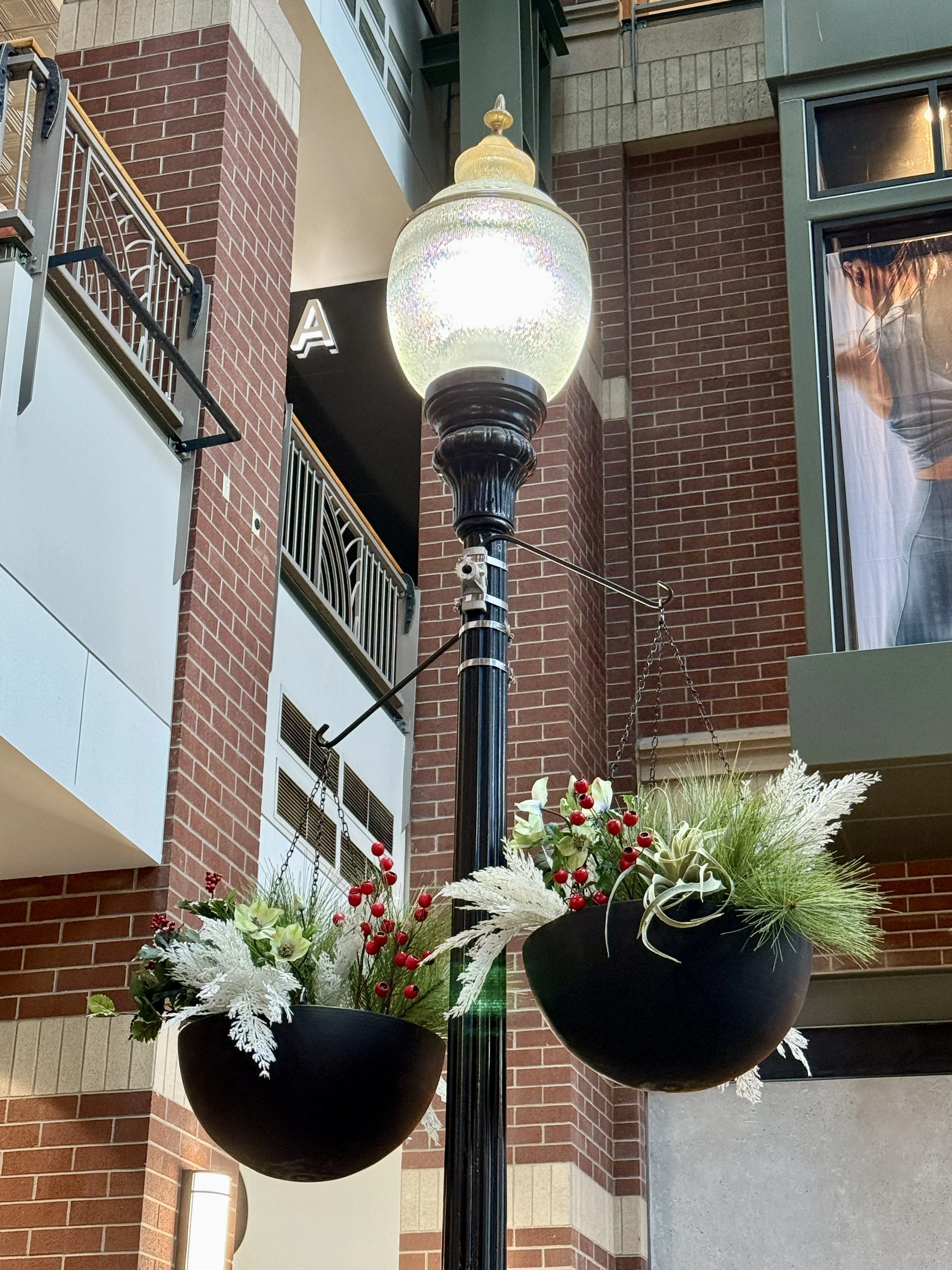 Holiday baskets with white and red accents, hanging in black baskets in a mall entrance. 