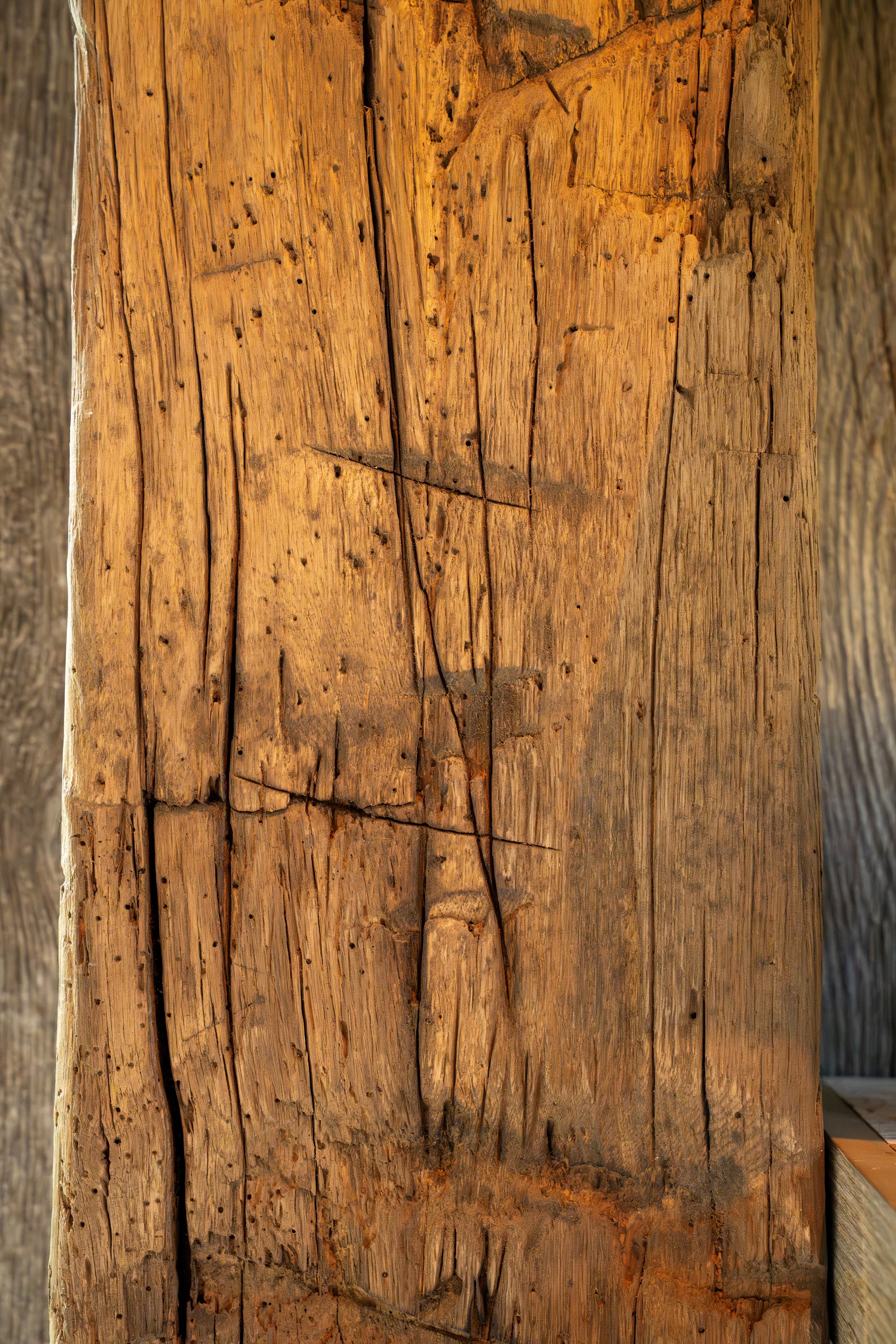 Close-up of a weathered wooden post with visible cracks and grain.