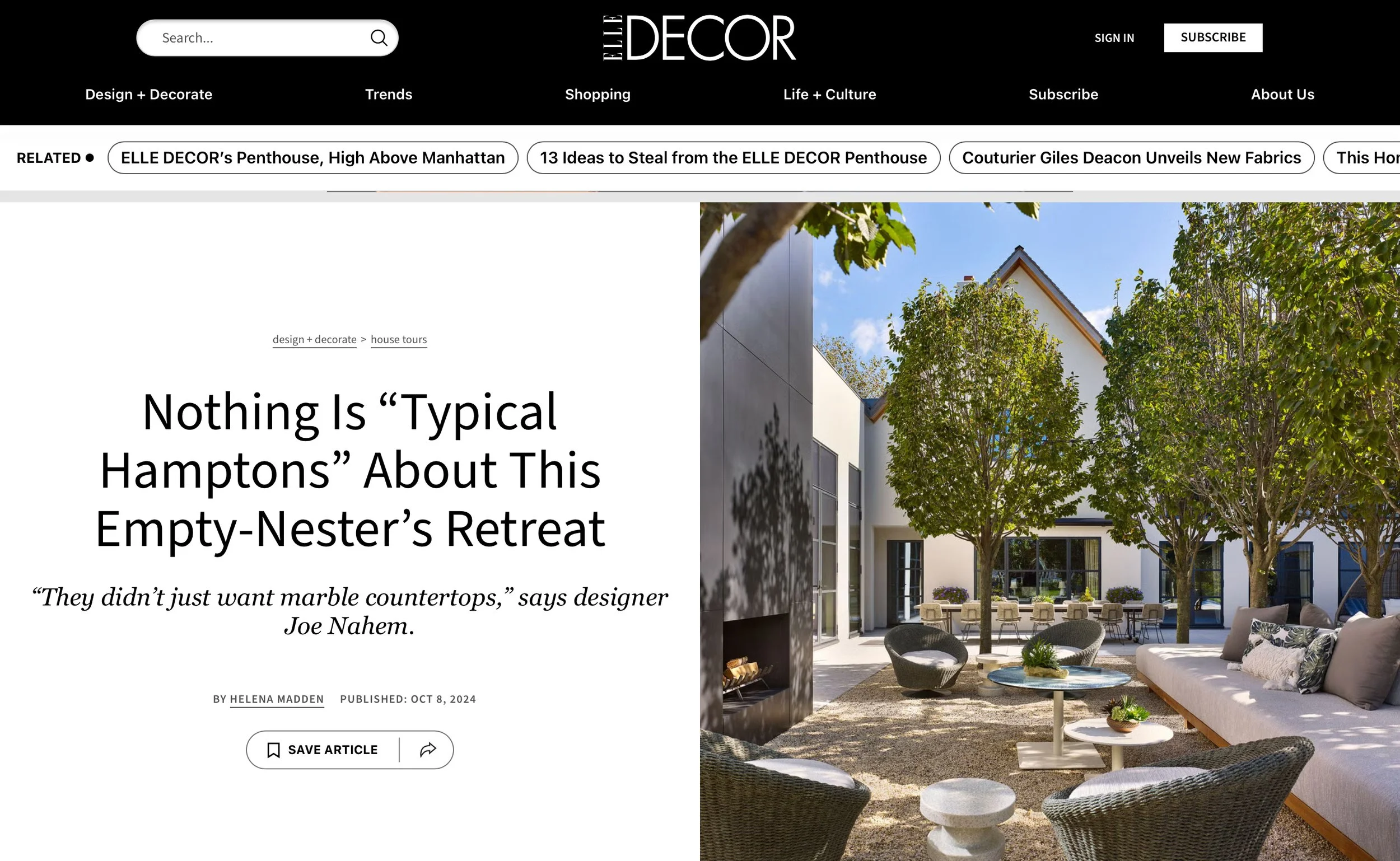 Outdoor courtyard with modern seating, trees, and a fireplace, in a home featured on Elle Decor.