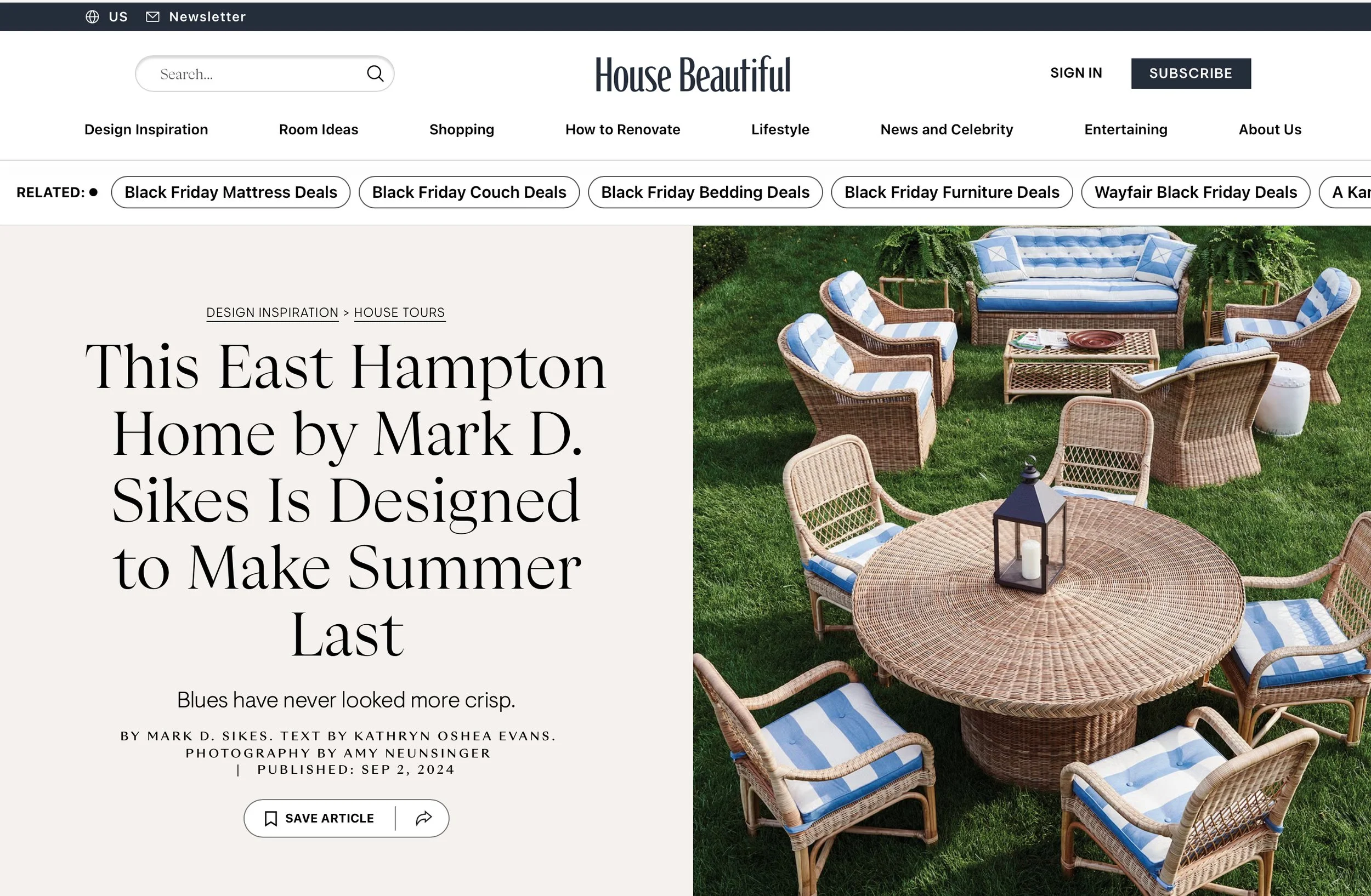 Outdoor patio furniture set on grass, including a round wicker table with lantern and candle, surrounded by wicker chairs and a sofa with blue and white cushions.