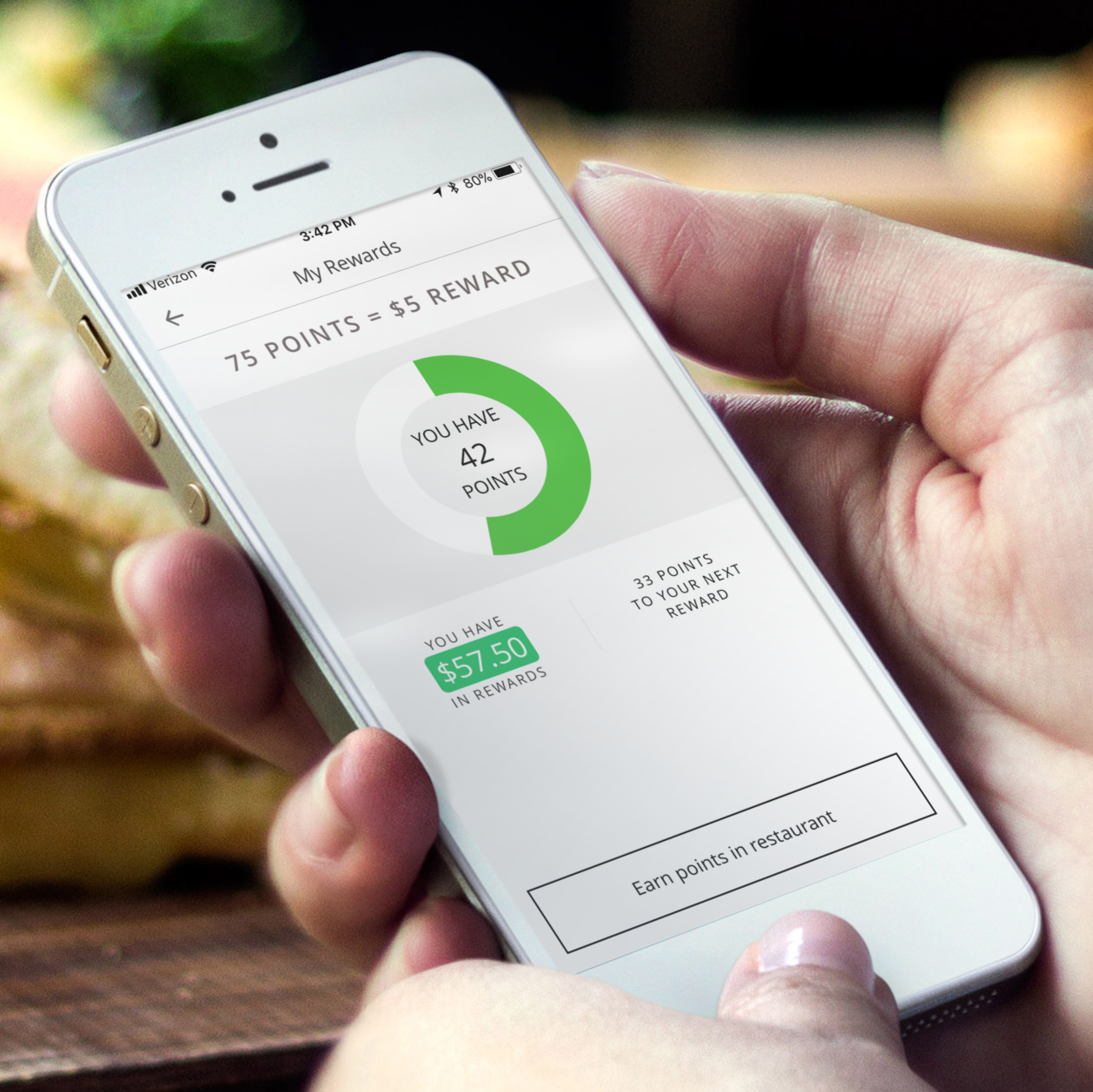 Smartphone screen showing a rewards program with 42 points, $57.50 in rewards, and a progress circle indicating points toward the next reward.