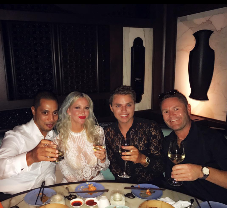 Four friends celebrating with drinks at a restaurant table.