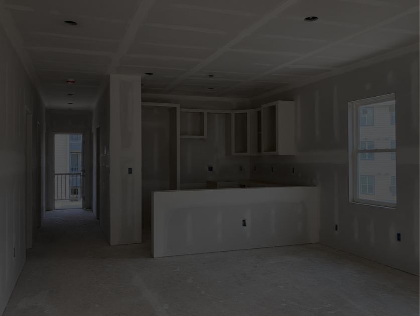 Unfinished room with kitchen cabinets, windows, and a hallway with a door leading outside