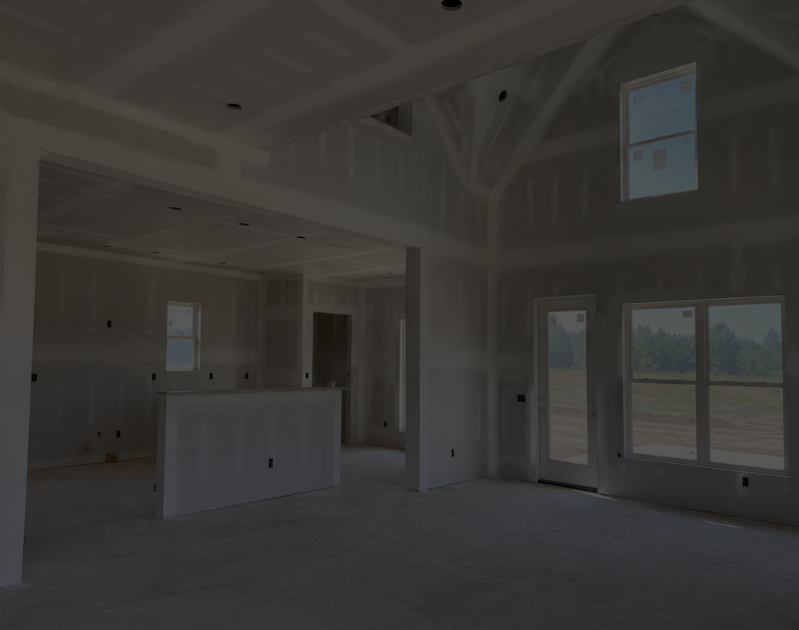 Interior of a new house under construction with unfinished drywall, large windows, and a sliding door.