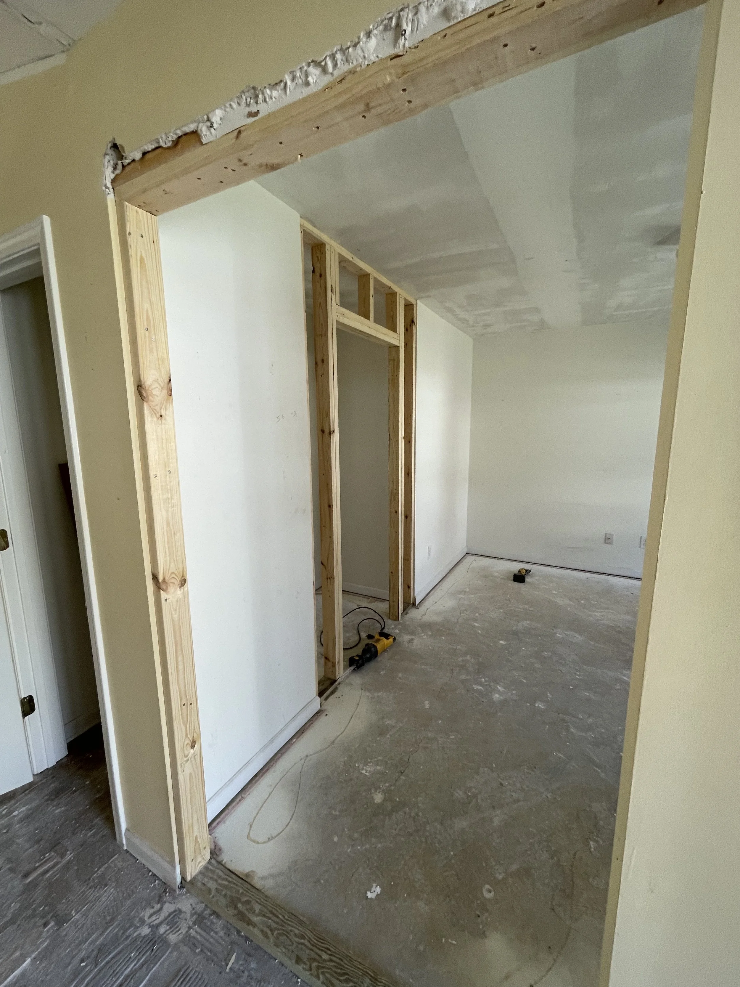 Interior of a house under renovation with an unfinished doorway framed with wood and a drywall ceiling in progress.