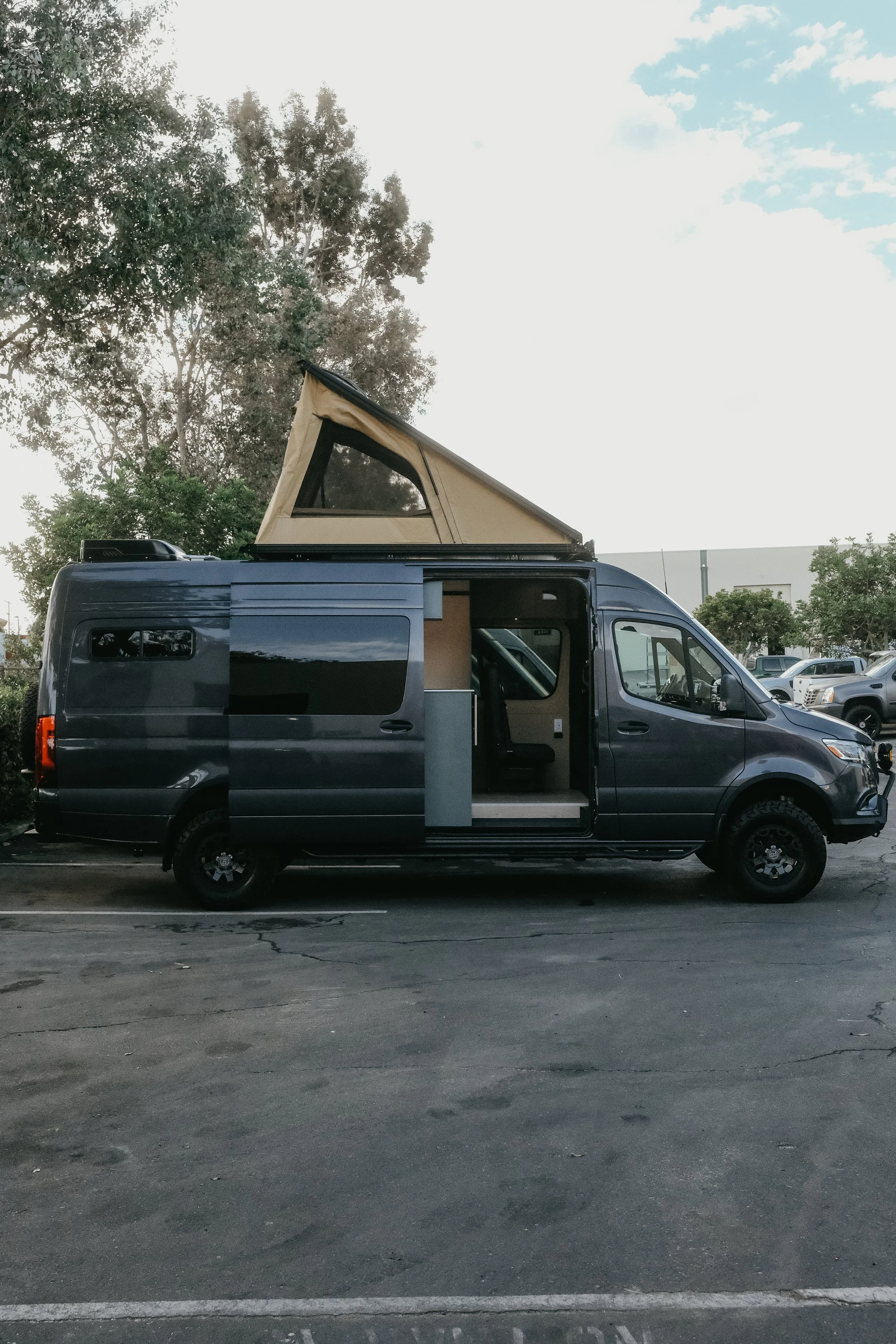 Side view of a Mercedes sprinter van with a super pacific roof top tent