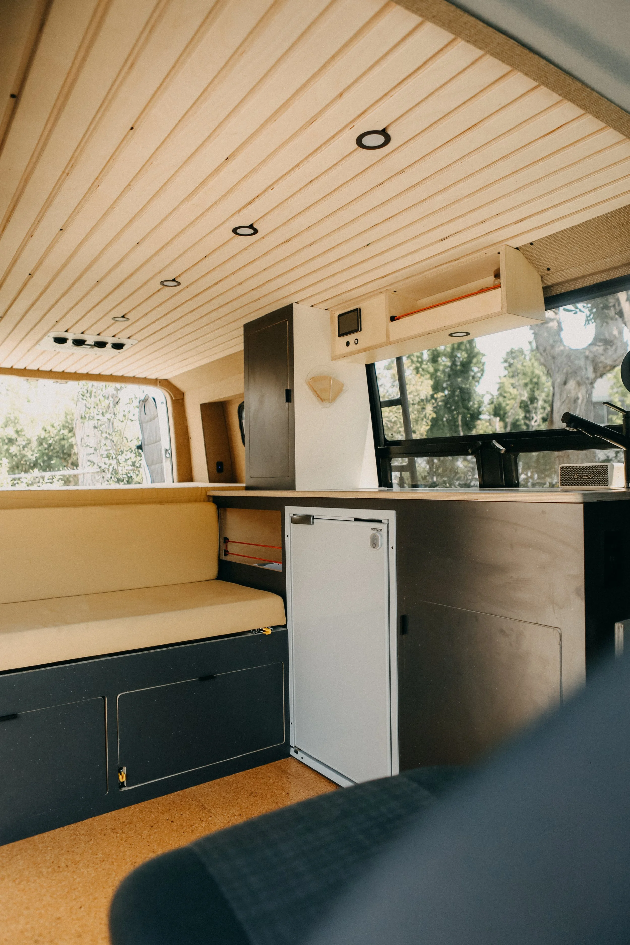 Premium custom ceiling panels in sprinter can featuring custom bench seating and kitchen.