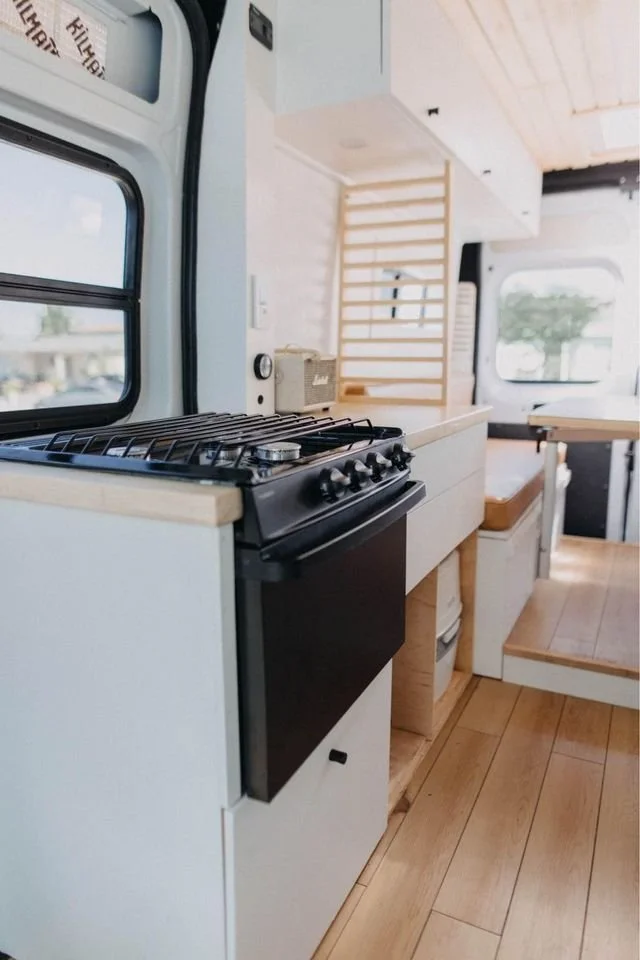 Modern custom van galley showing precision-crafted cabinetry and stove oven inside mercedes sprinter van