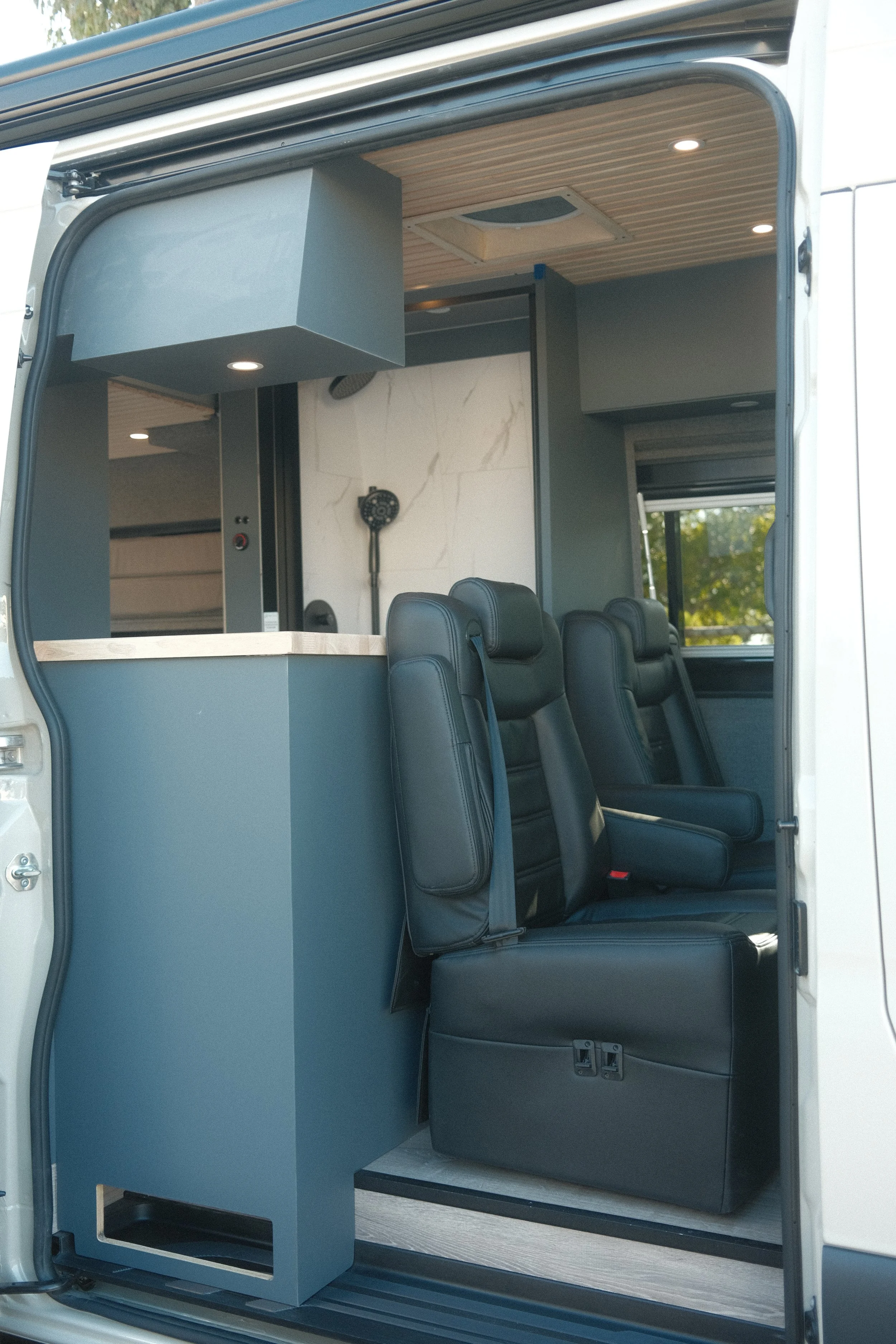 Premium custom van lounge layout featuring multi-functional design and high-end seating, kitchen area, and shower