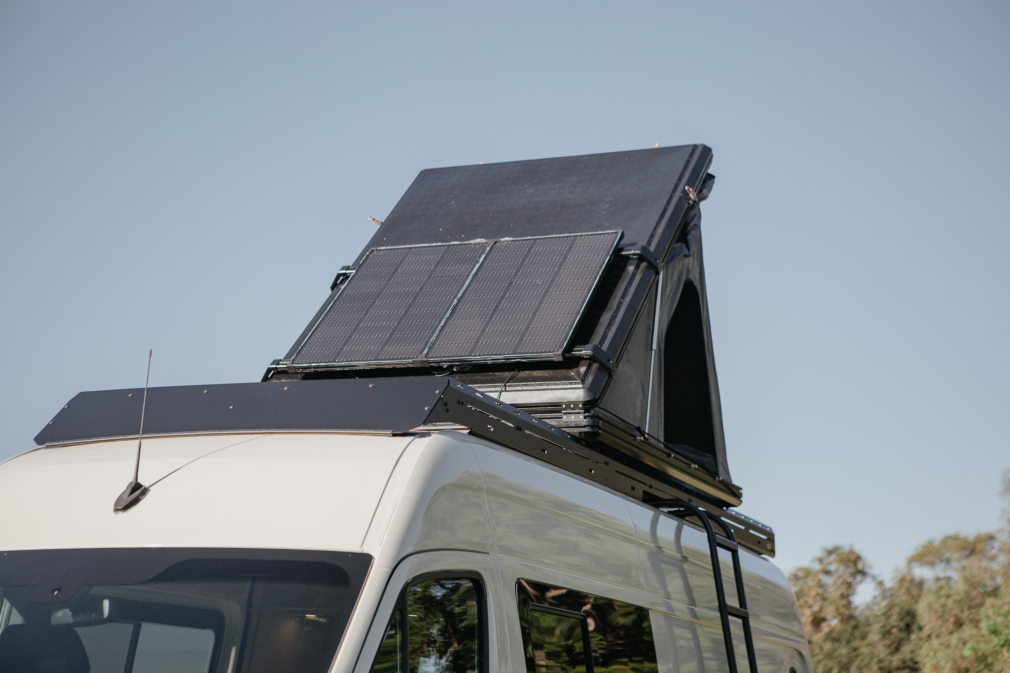 Mercedes sprinter van with a close up on solar panels and a pop up super pacific tent on the roof
