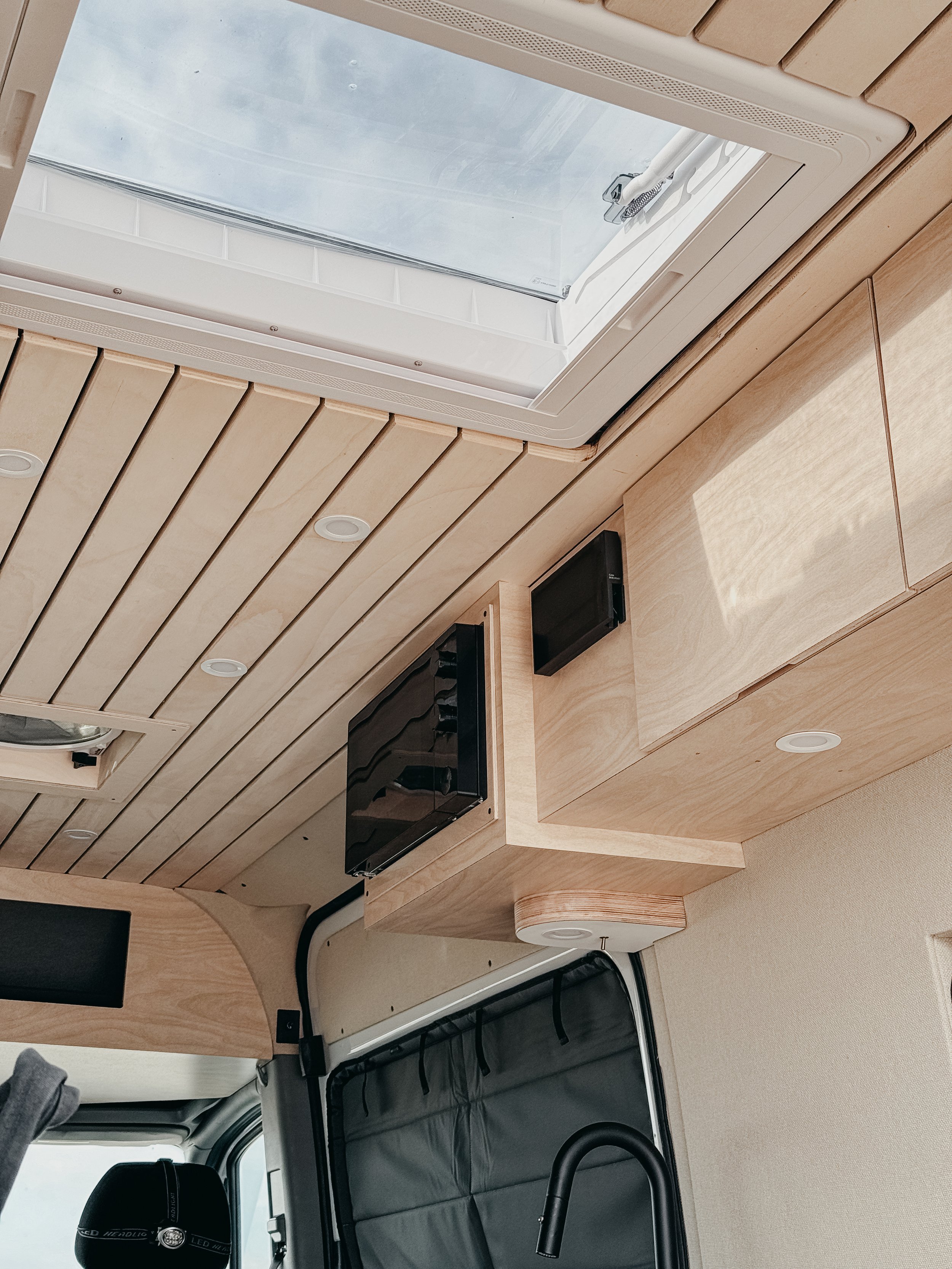 Custom scandanavian modern ceiling panels featuring a sky light, custom storage cabinets with overhead microwave 