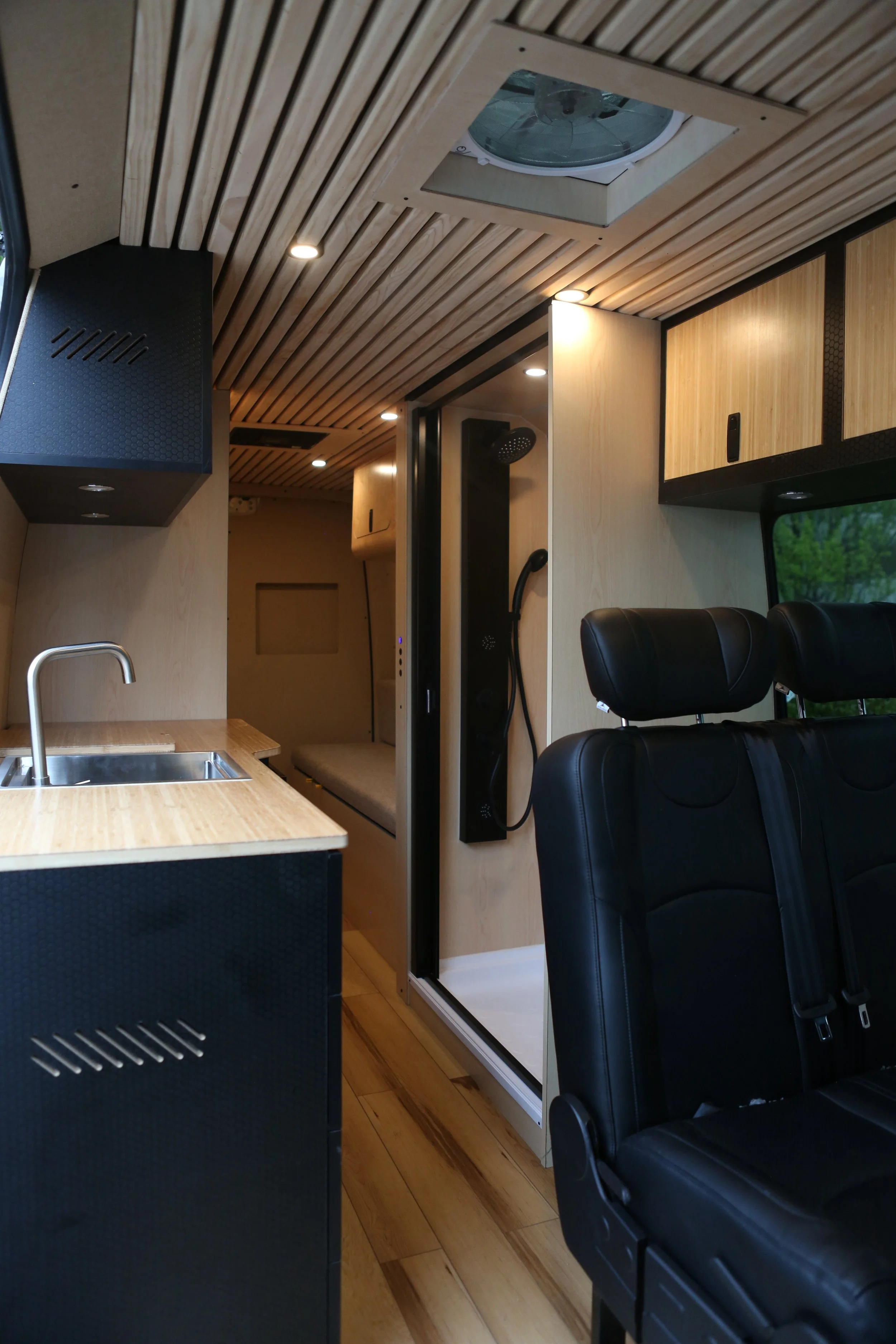 Bespoke conversion van galley featuring a flush-mount induction cooktop and architectural hardware.