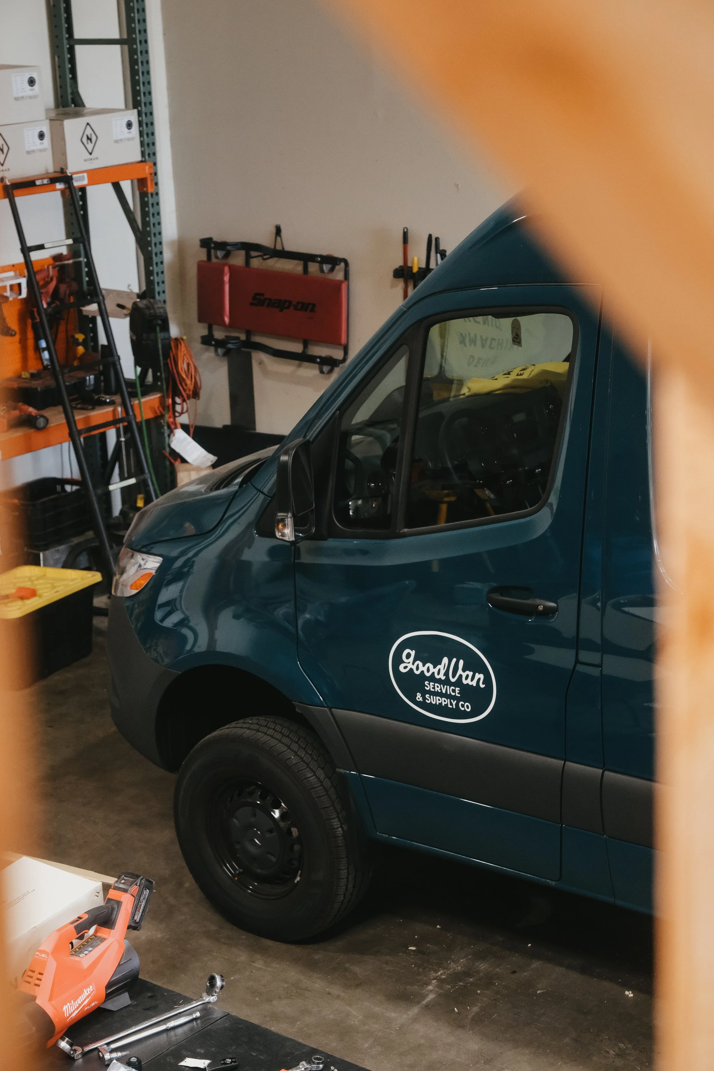 Aqua blue Mercedes sprinter van inside The Good Van Supply Co garage for affordable sprinter van conversion.