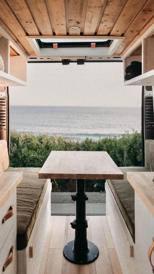 Custom mercedes sprinter modular bench seating, table, and ceiling panels with a seaside view.