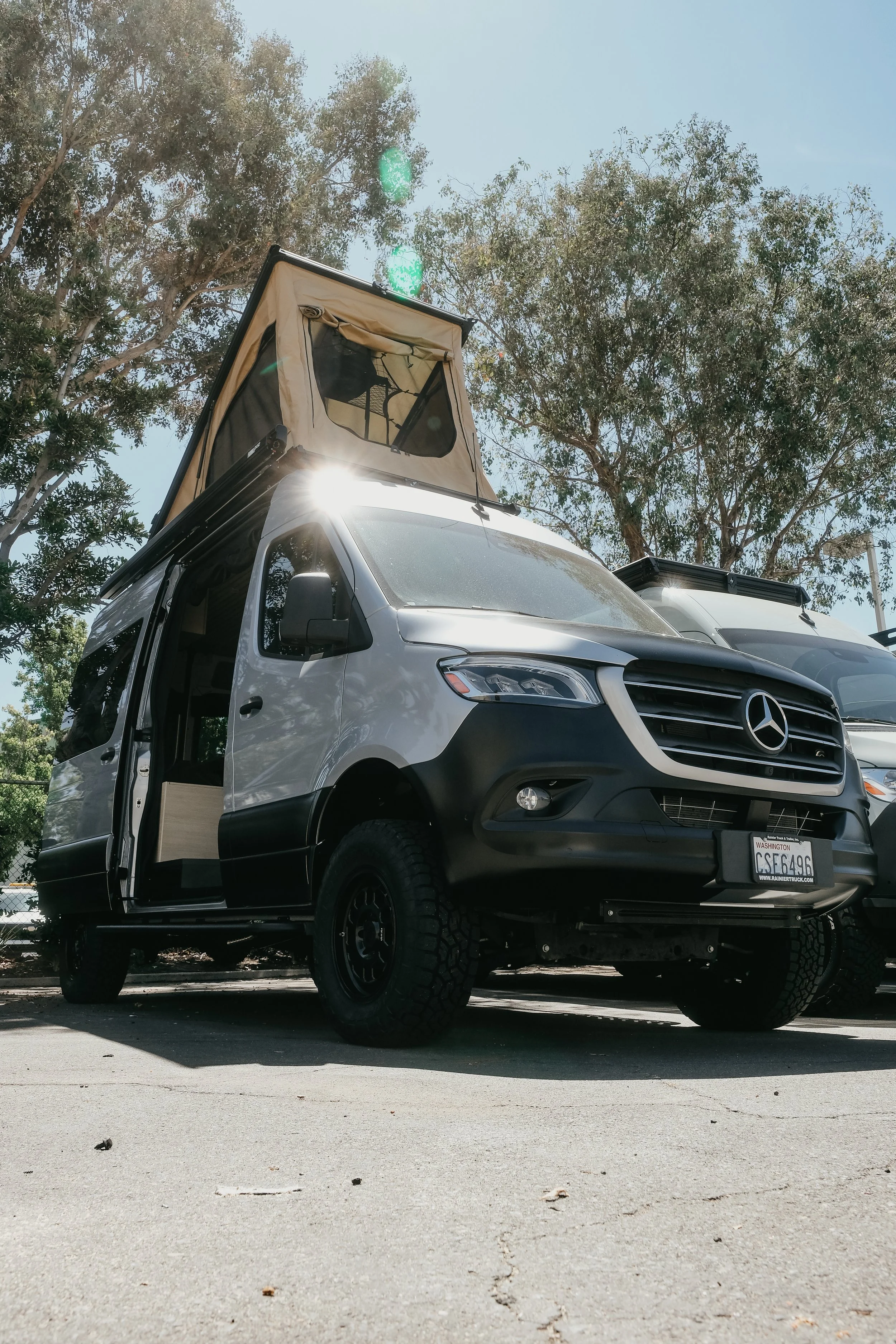 Side, upward view of a Mercedes sprinter can with a super pacific roof tent popped up 