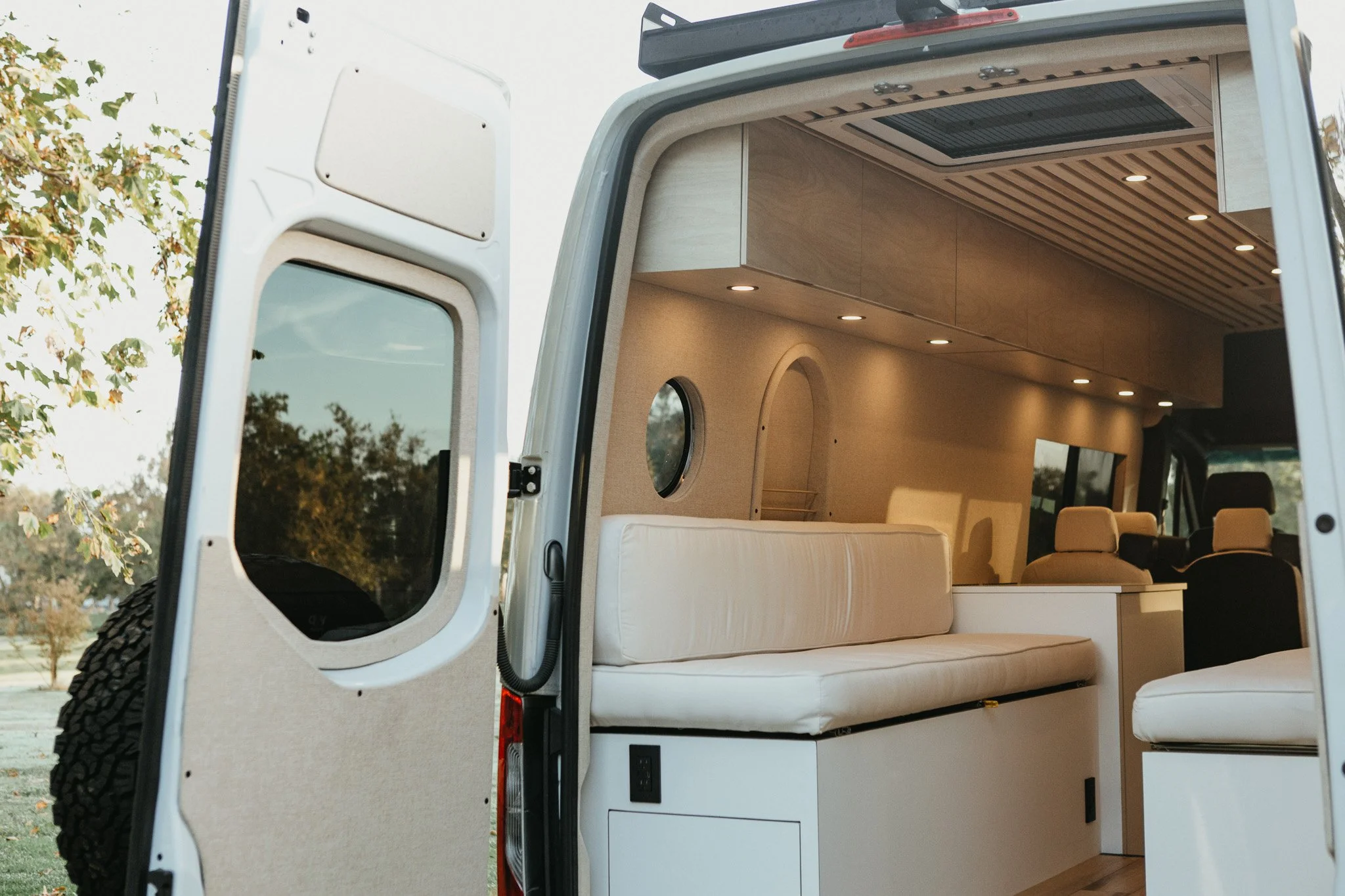 Contemporary Sprinter camper van living area featuring a custom sofa with built-in storage.