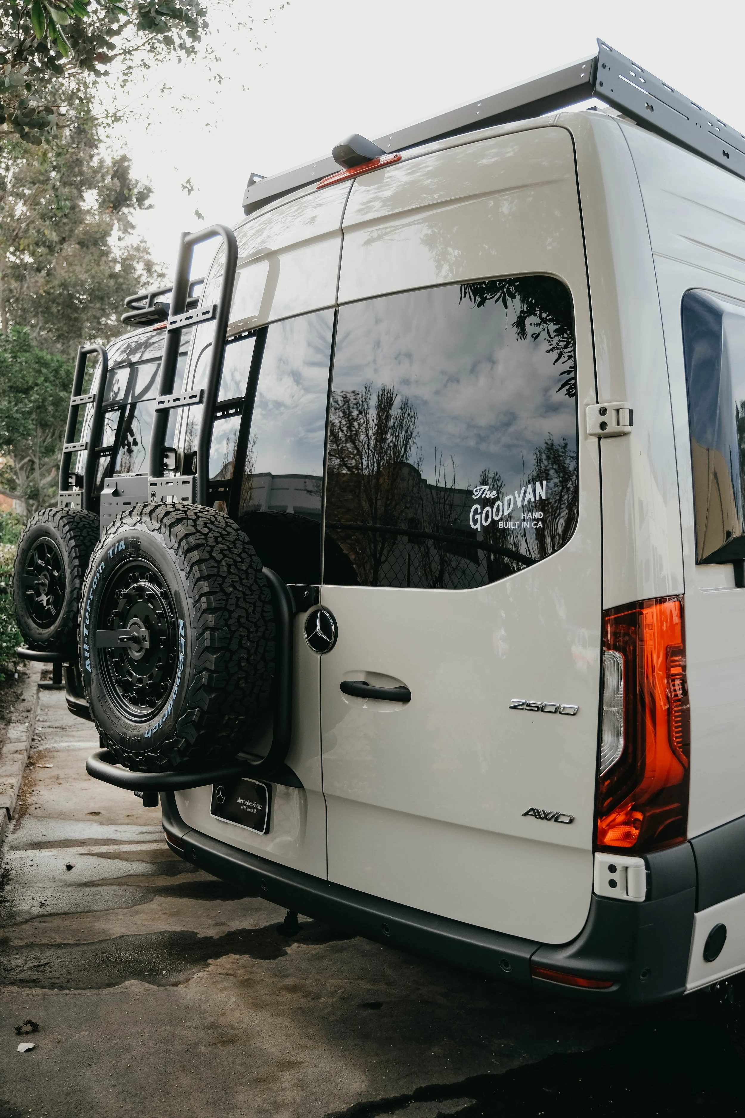 Rear view of a Mercedes sprinter van with a ladder and tire carrier