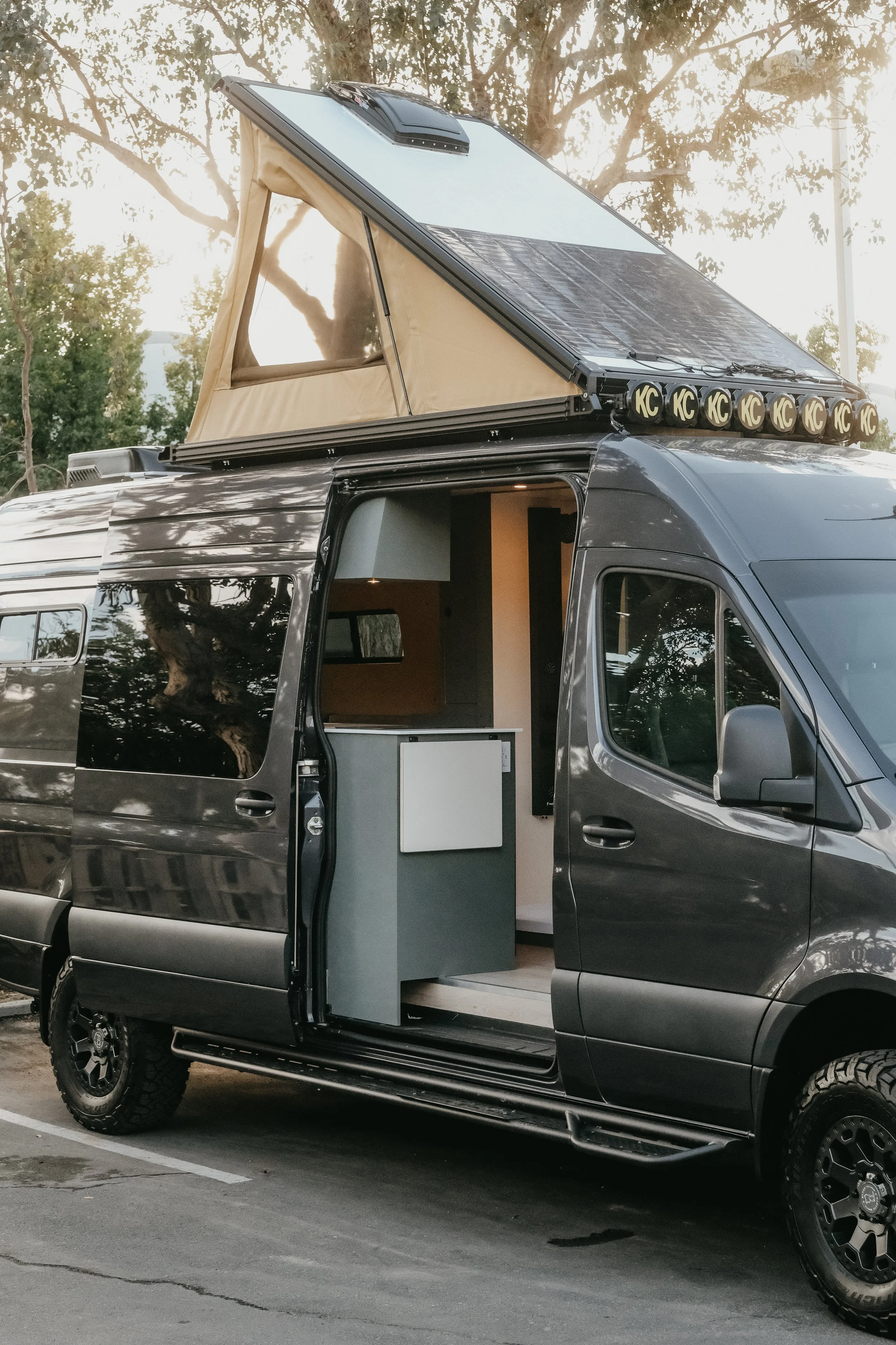 Side view of a Mercedes sprinter van with a super pacific roof top tent and LED light bars and custom van interior. 