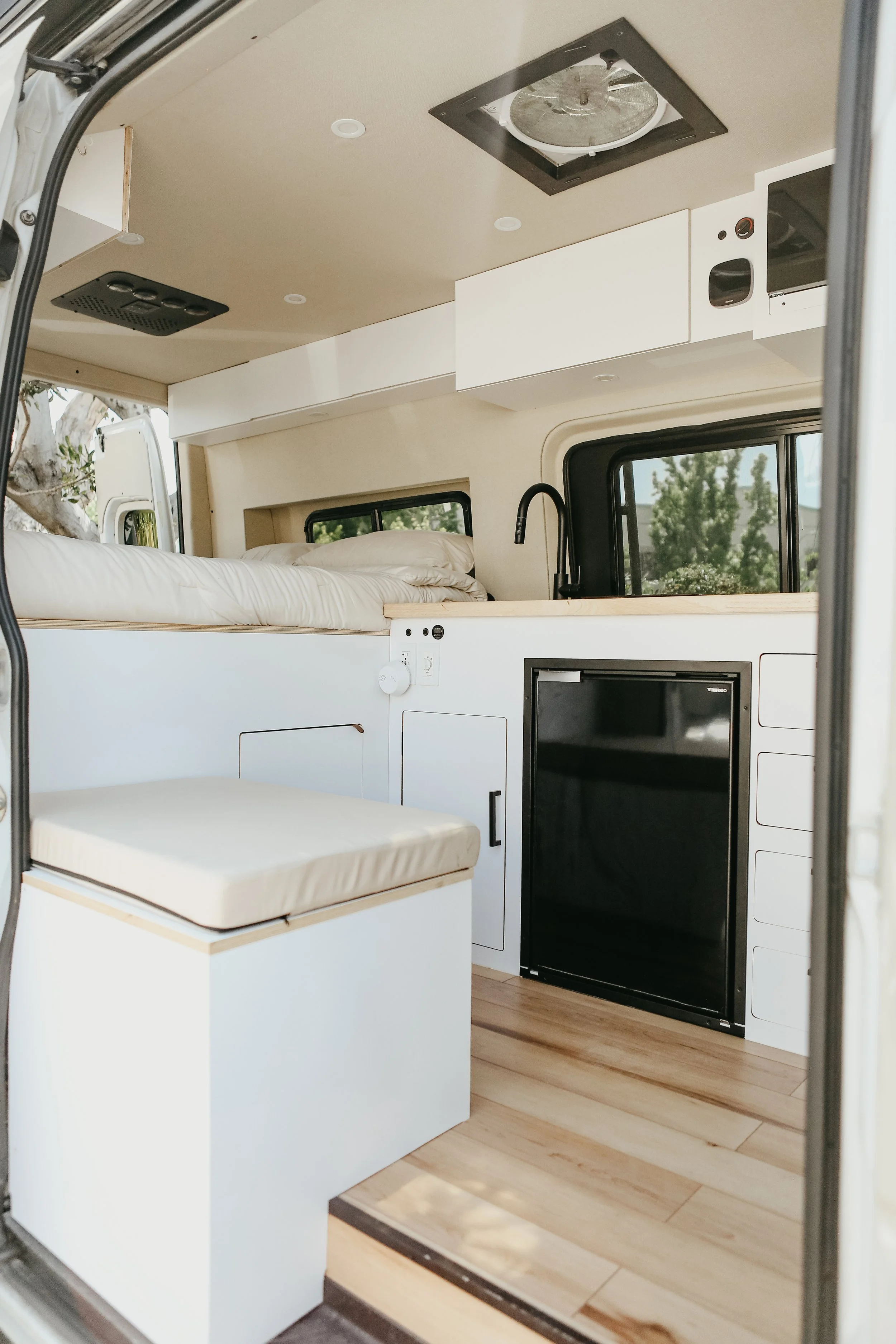 Bespoke Mercedes Sprinter platform bed layout featuring under-bed gear garage storage and kitchen.