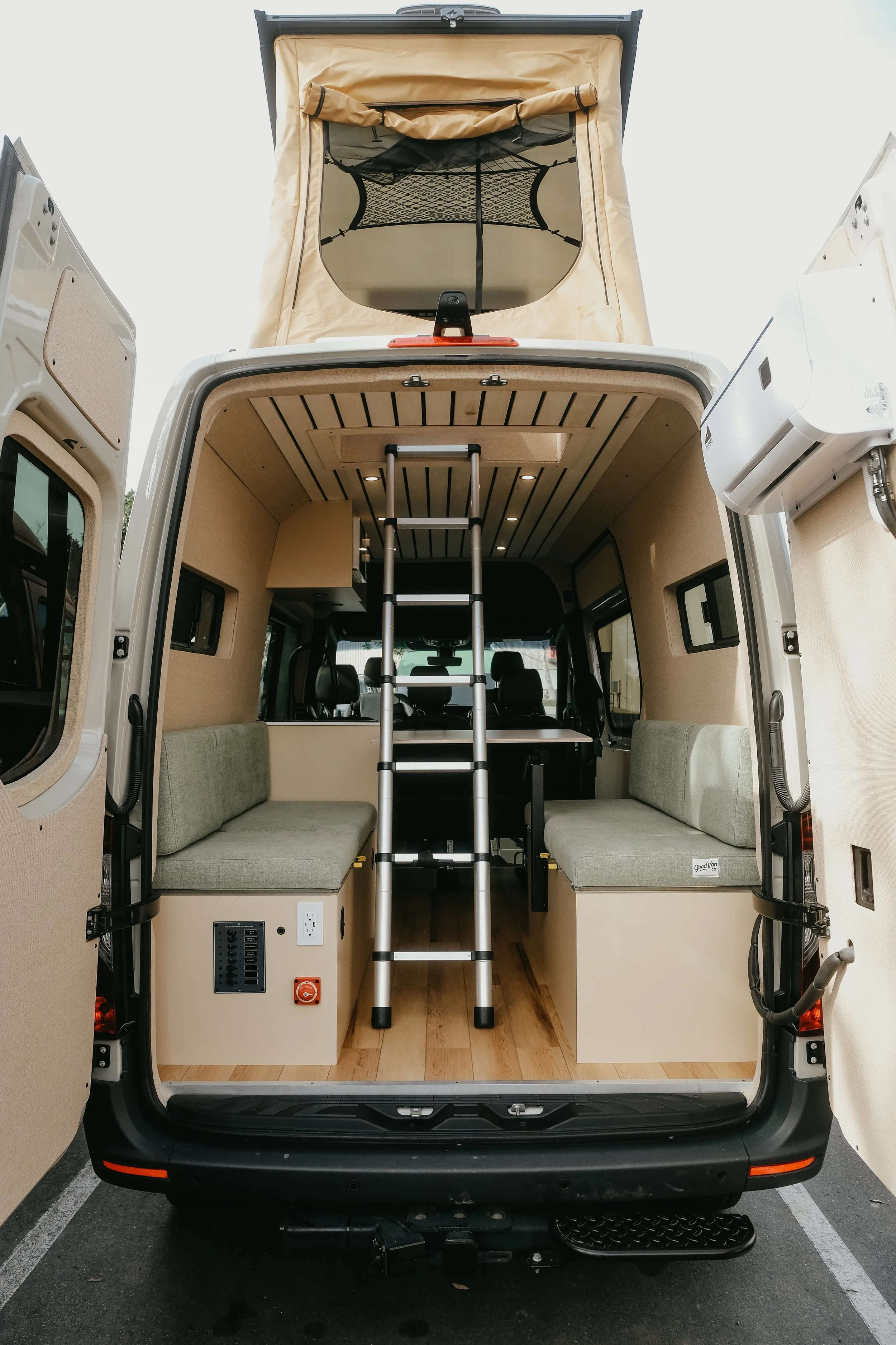 Rear view of a custom interior build for sprinter van with two custom benches, ladder leading up to the pop up tent 