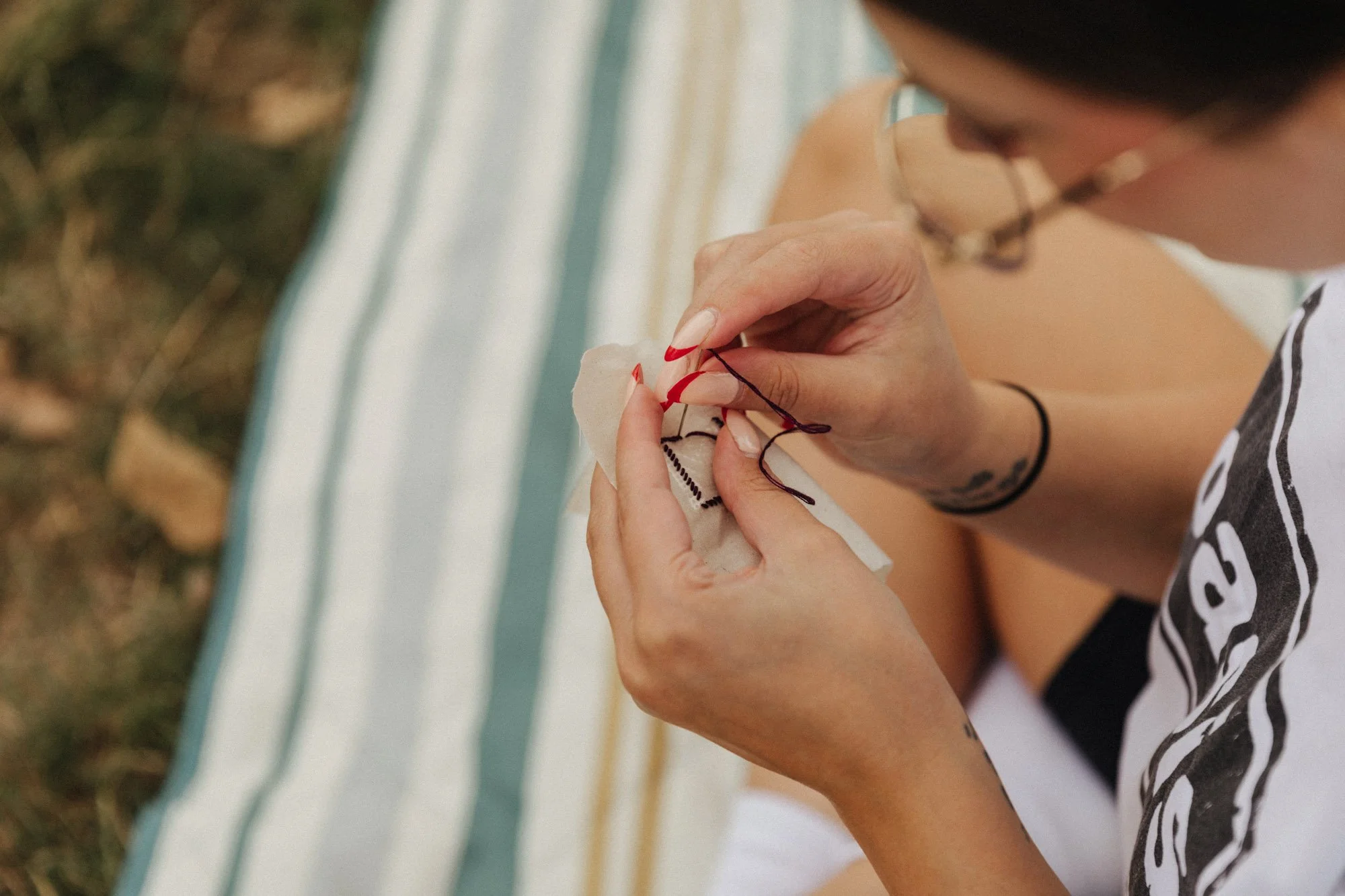 Embroidering hands outside on a blanket.