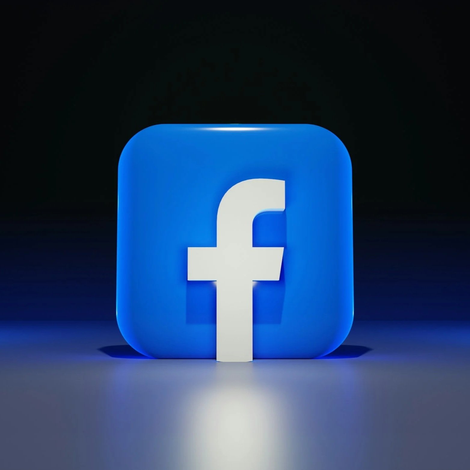 Facebook logo illuminated in blue light on a dark background.