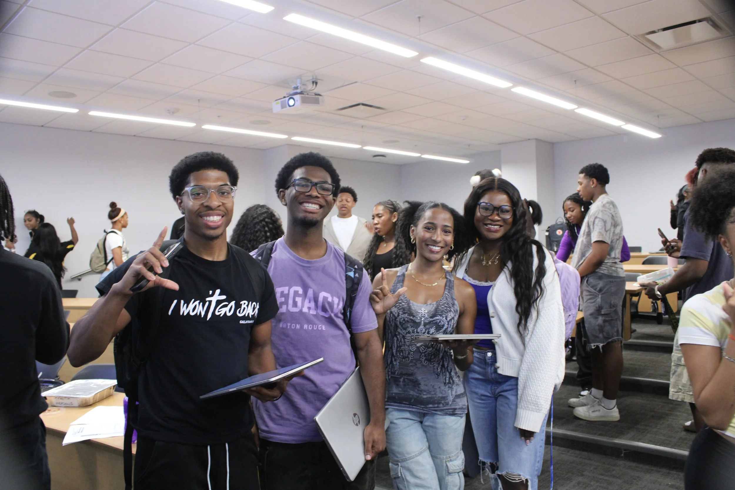 A group of casually dressed men and women posing together indoors while smiling.