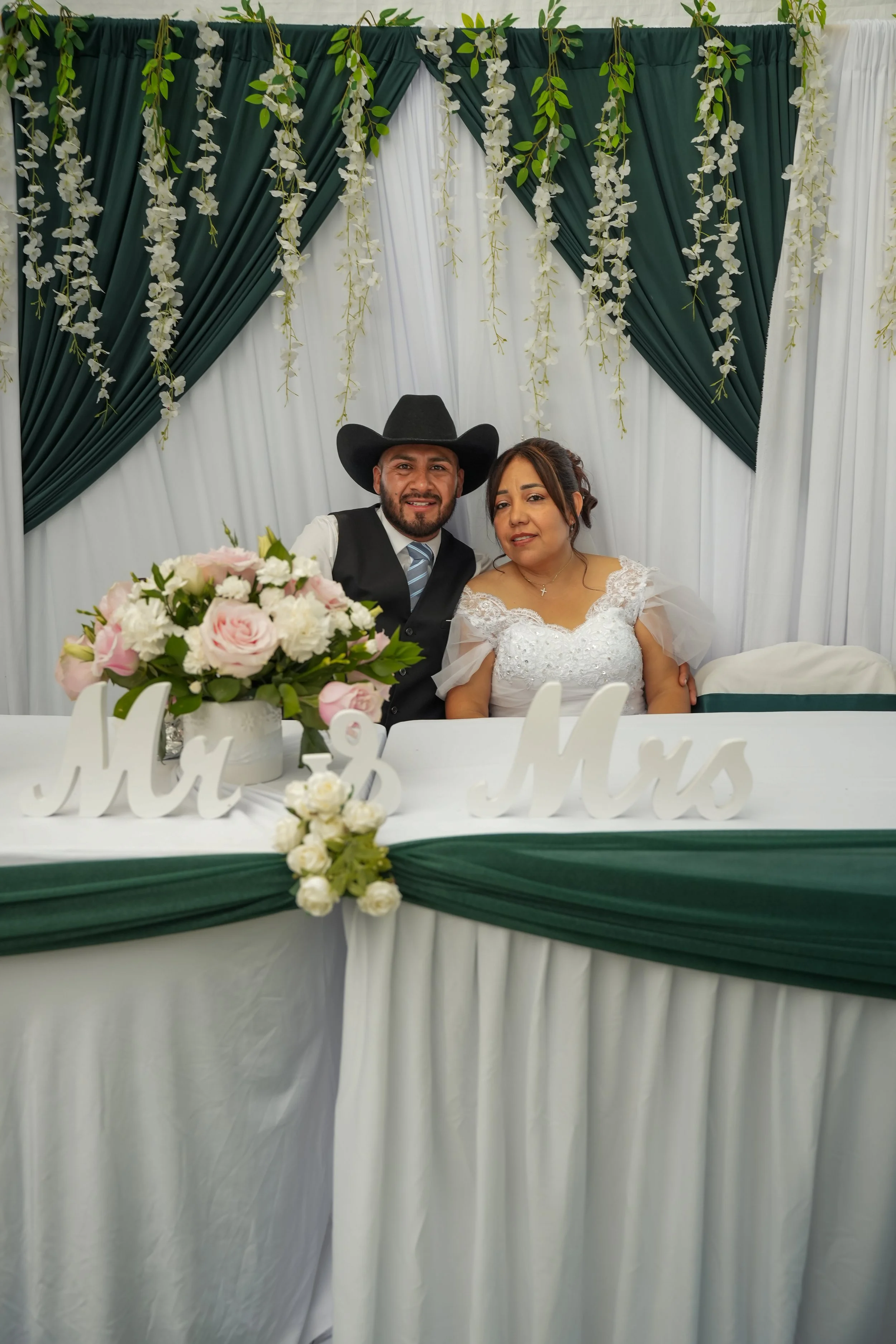 Bride and groom in wedding attire standing in front of a fountain during daytime