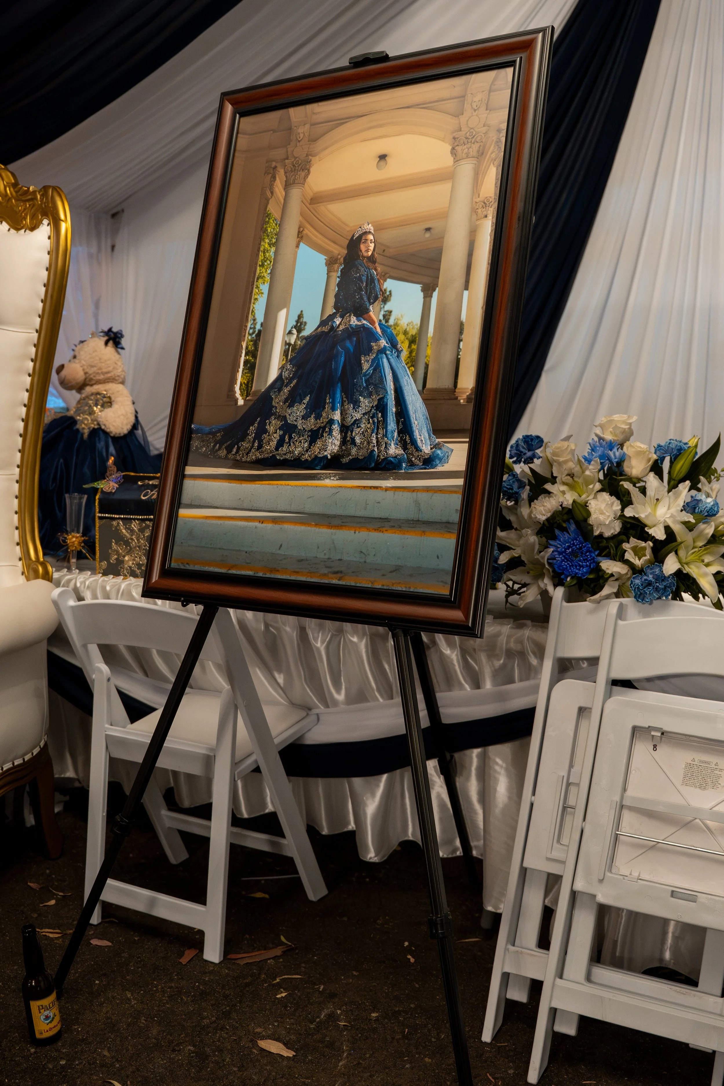 Empty white picture frame on light wood floor with a green leaf and shadow to the left